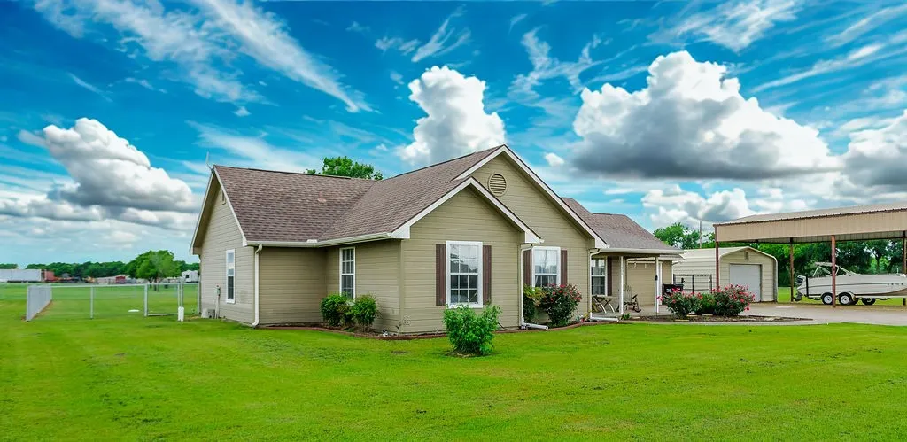 Single-story residence featuring light olive siding, a brown shingle roof, and white-trimmed windows with dark brown shutters