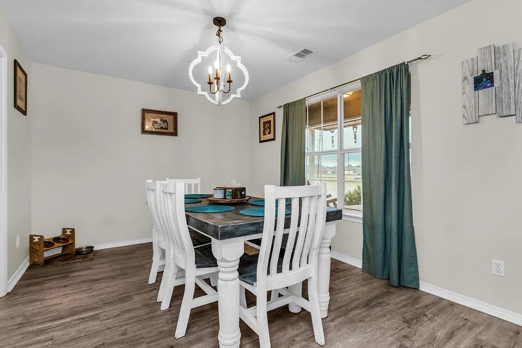 Dining area featuring wood-finish flooring, a contemporary chandelier, and a window with a multi-pane design