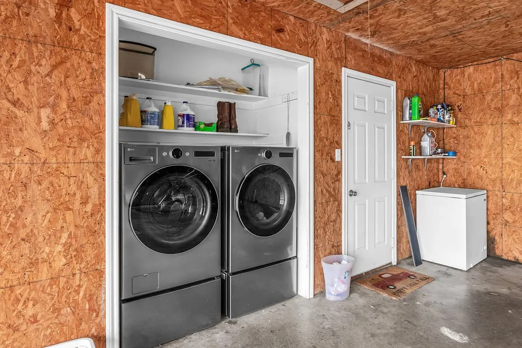 Dedicated laundry area featuring a built-in closet with shelving and a concrete floor
