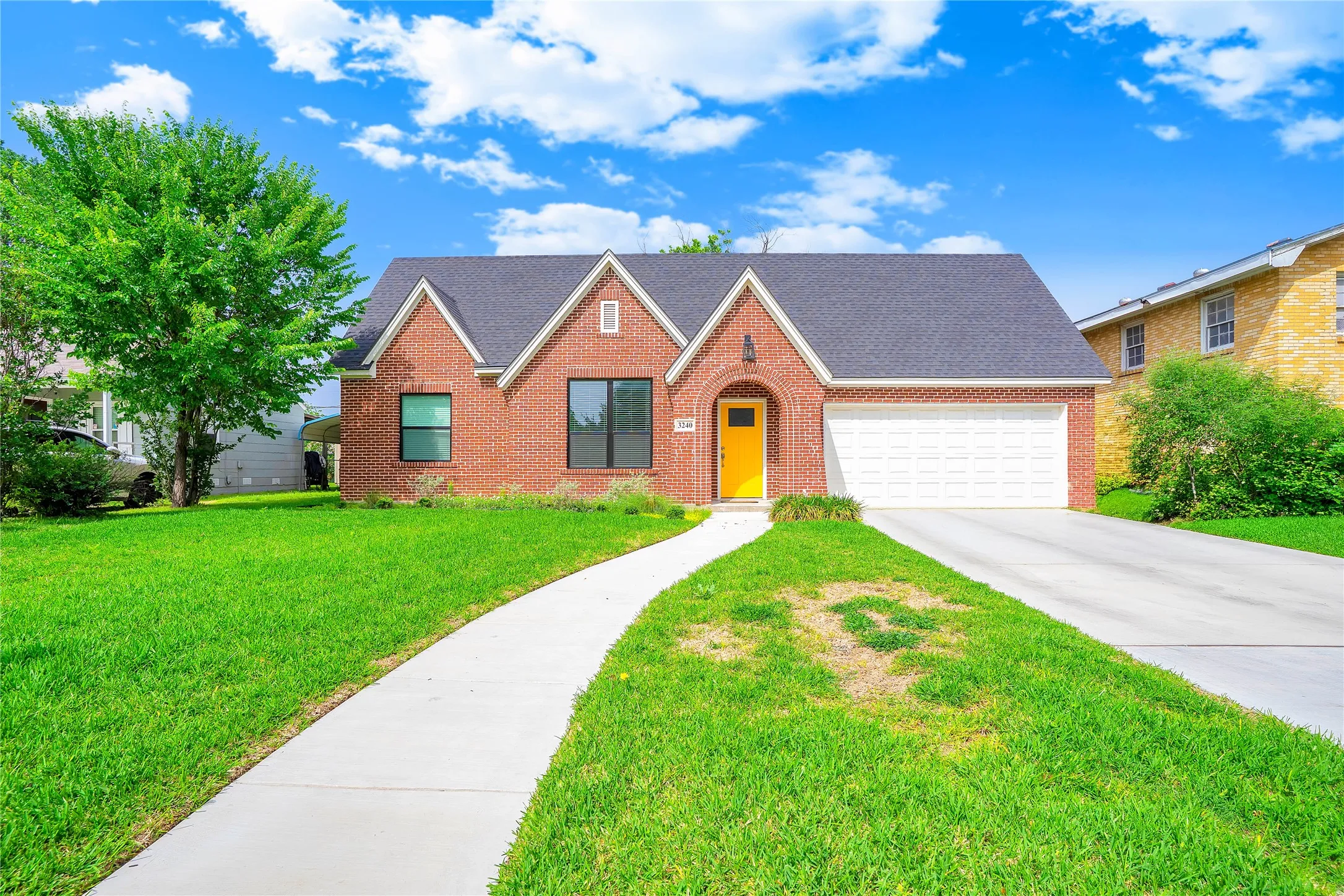 Brick exterior with contrasting dark roof shingles and a bright yellow front door