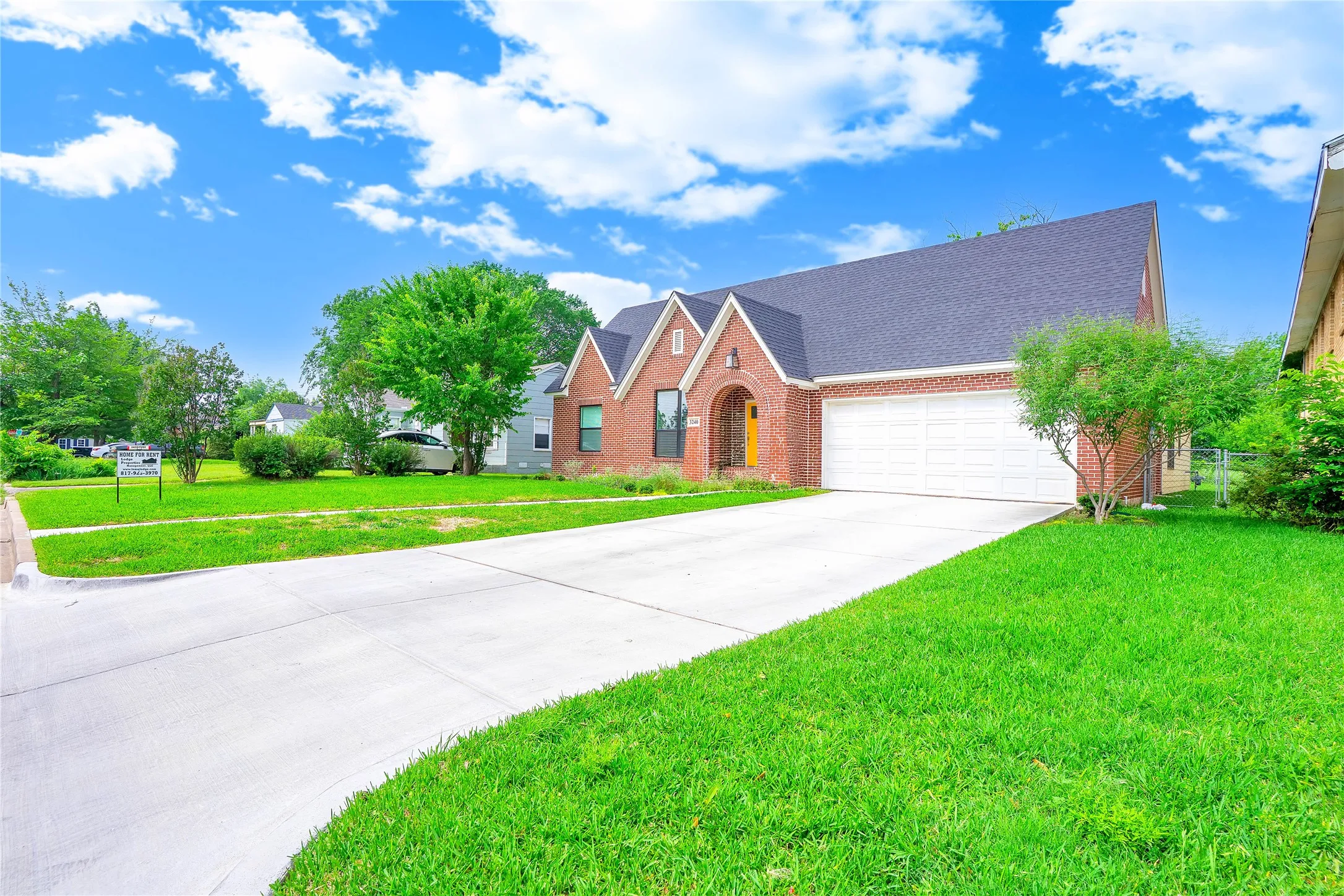 Brick exterior featuring an arched entryway, gabled rooflines, and a two-car garage