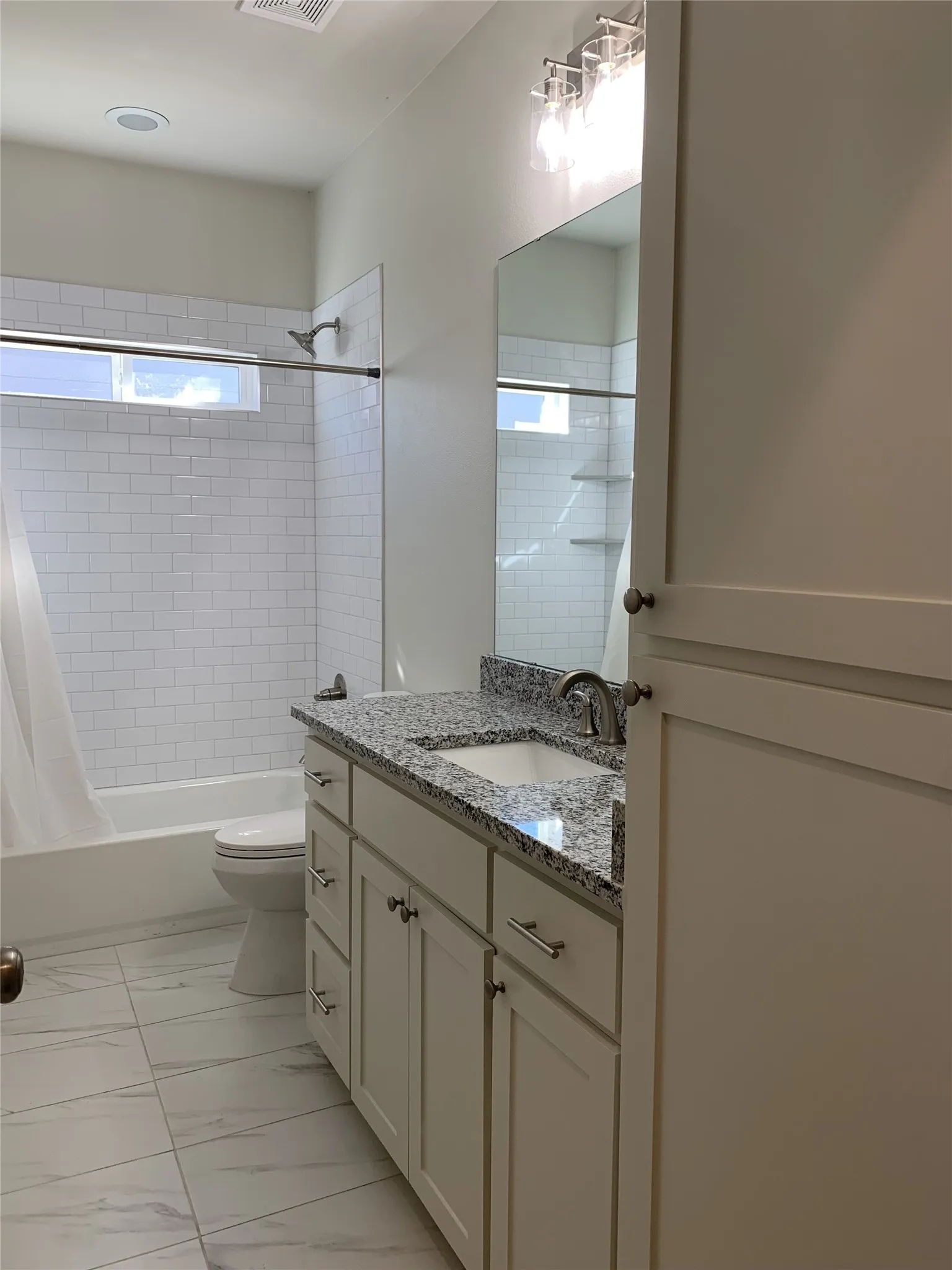 Bathroom featuring a single vanity with stone countertop, undermount sink, and chrome fixtures