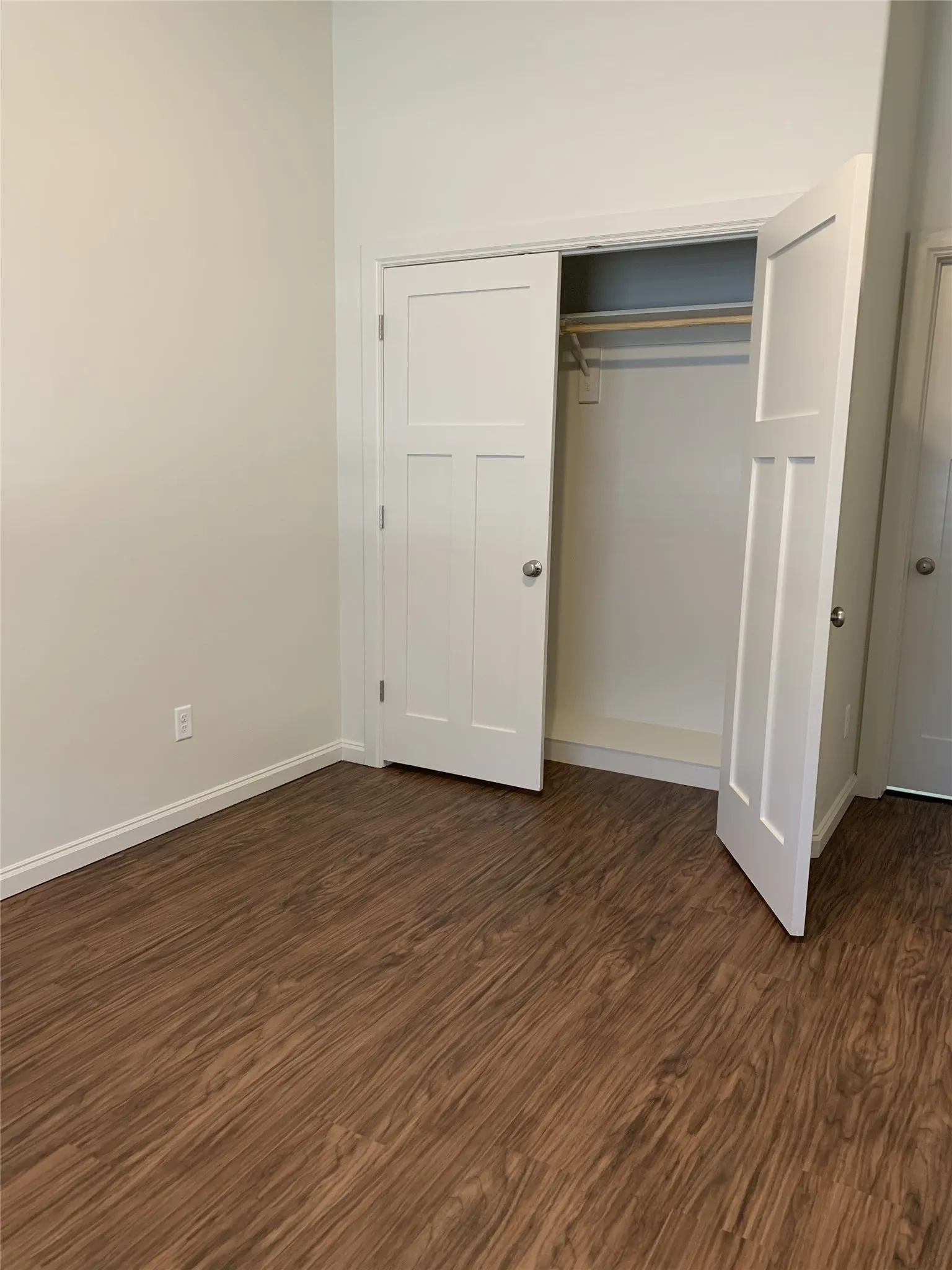 Room featuring wood-finish flooring, light-toned wall paint, and white baseboards