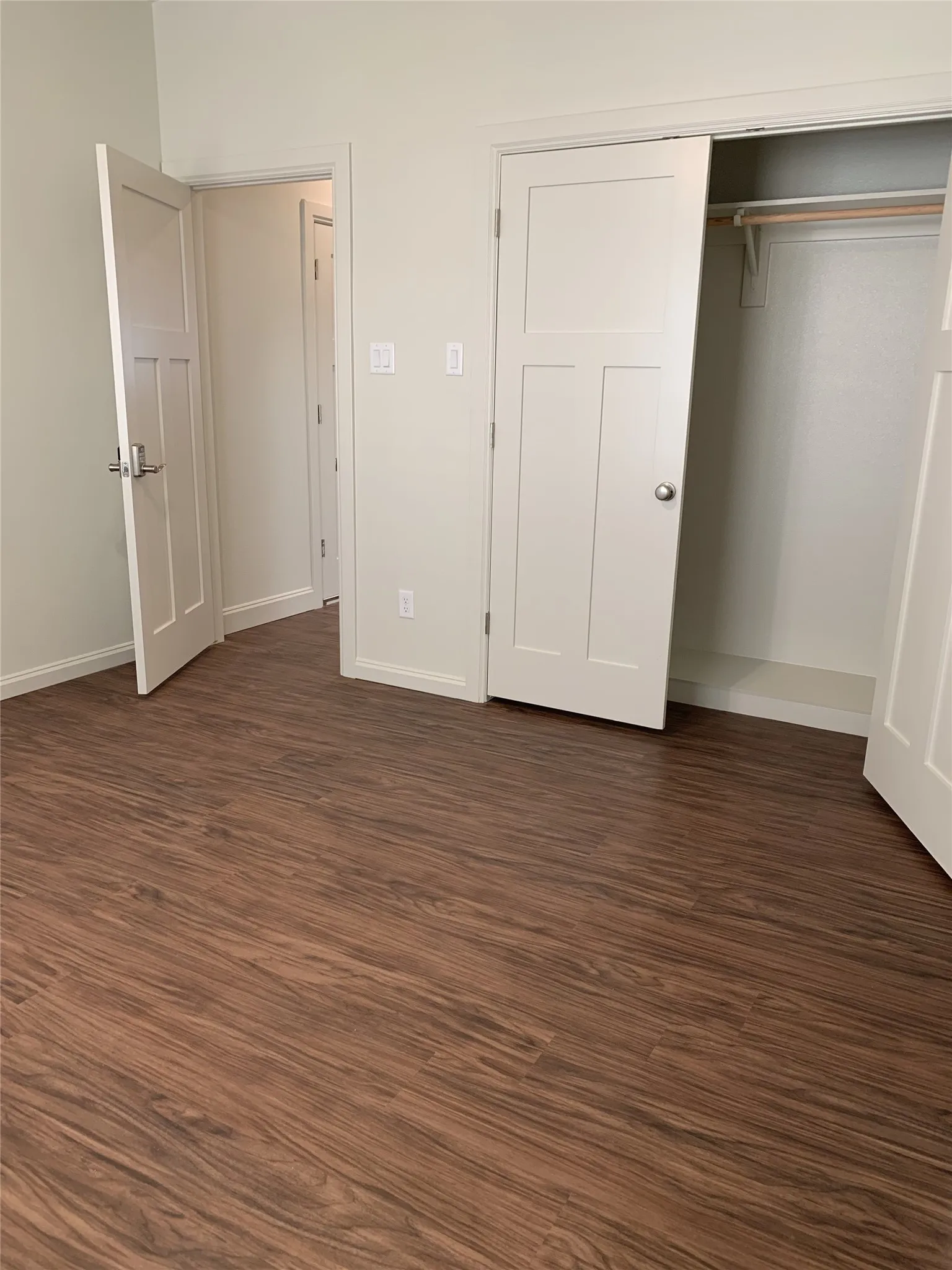 Interior room featuring wood-finish flooring, light neutral wall paint, and white trim