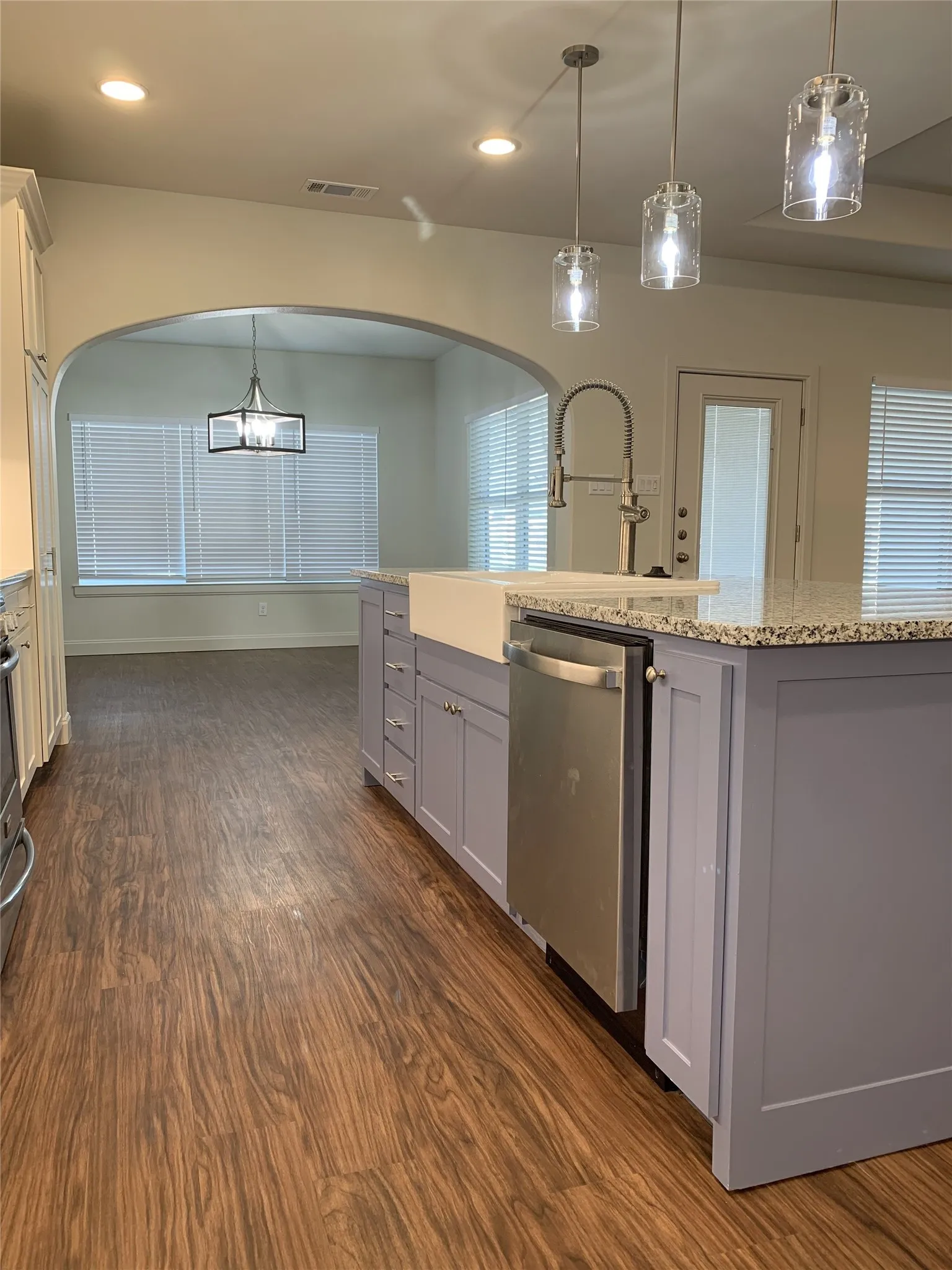 Kitchen island with light purple cabinetry, a farmhouse-style sink, and a stainless steel dishwasher