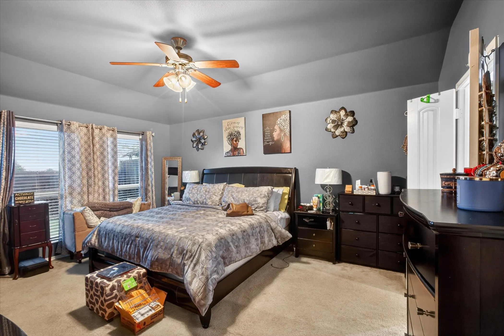 Carpeted room featuring a ceiling fan with integrated lighting, multiple windows with blinds and curtains, and neutral wall paint