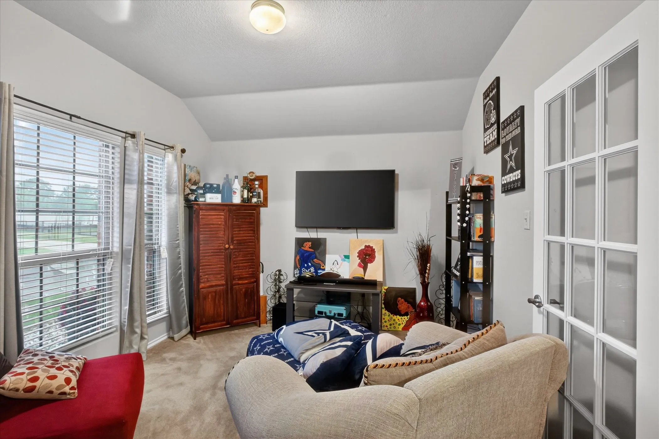 Living area featuring vaulted ceilings, light gray wall paint, and carpet flooring