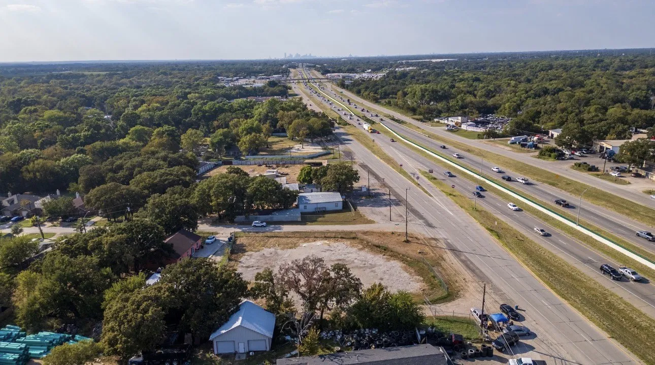Aerial perspective showcasing expansive wooded areas with a prominent multi-lane highway corridor