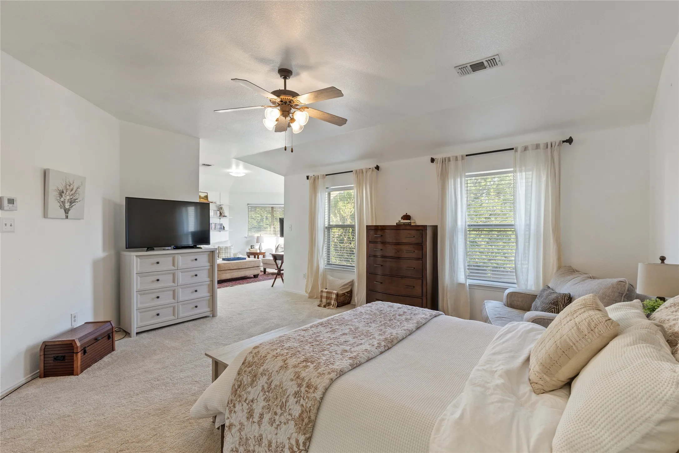 Carpeted room with vaulted ceilings and a ceiling fan