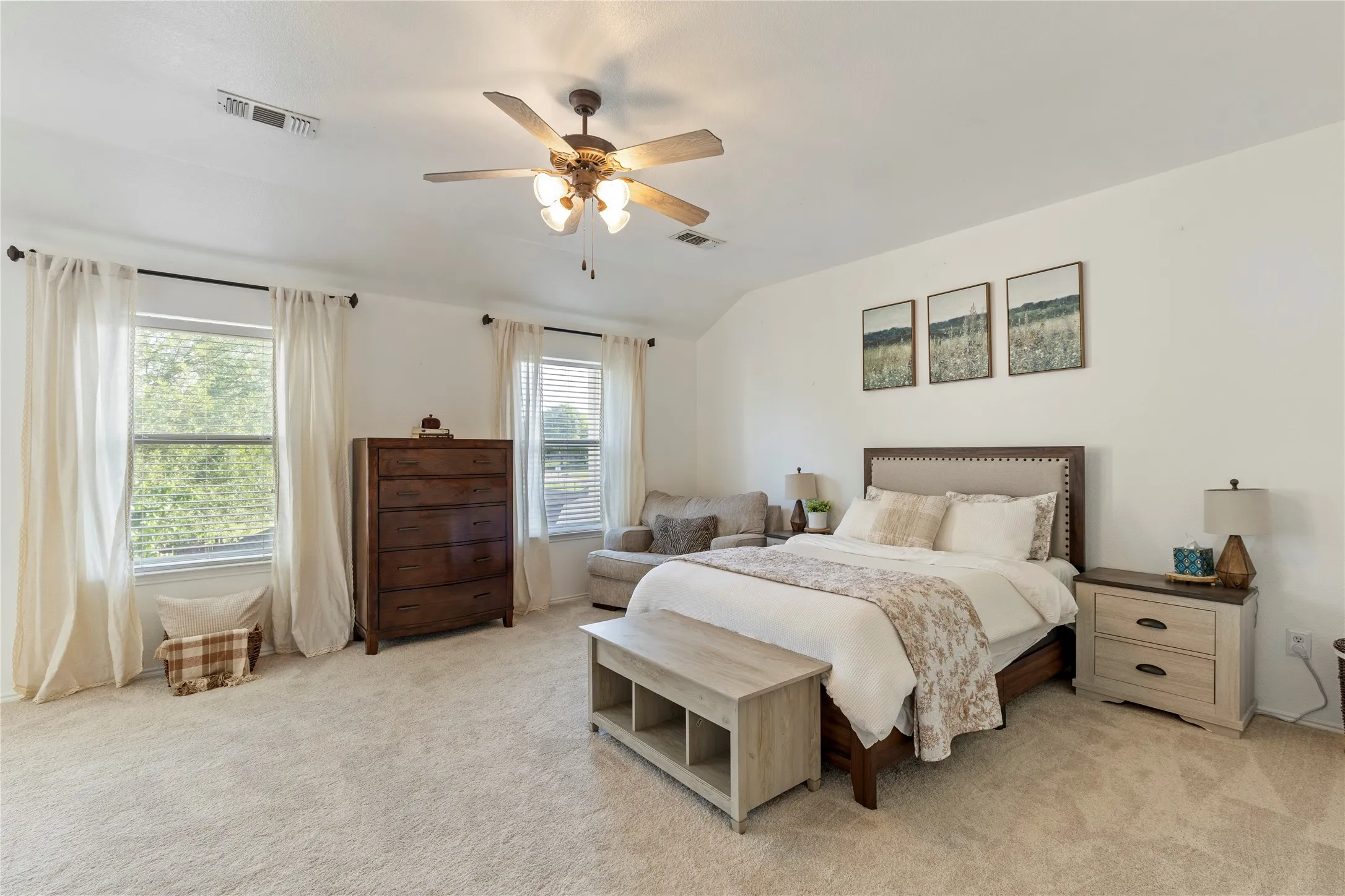Spacious room featuring light-colored carpeting, multiple windows providing natural illumination, and a ceiling fan with integrated lighting