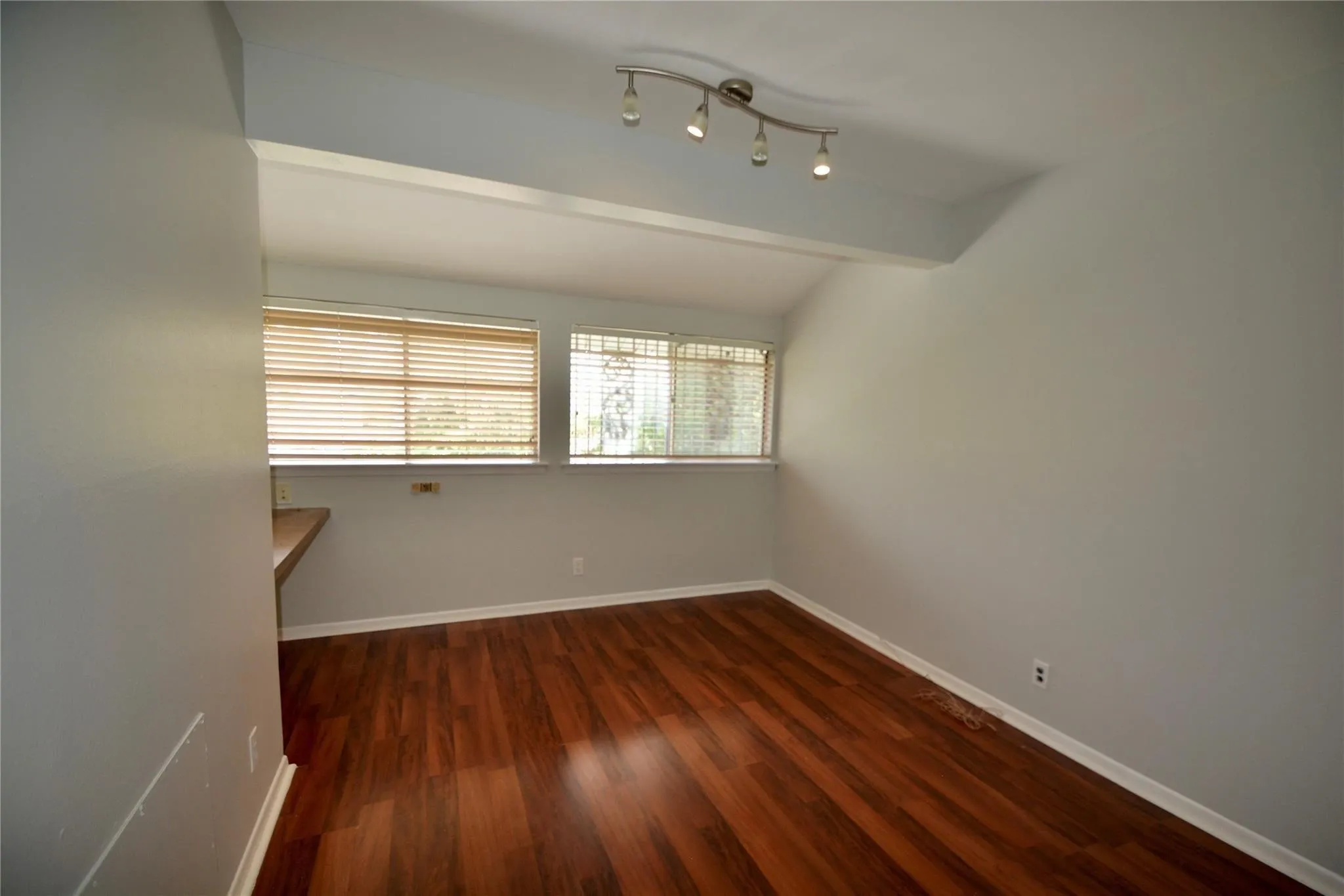 Room featuring wood-finish flooring, light grey painted walls, and white baseboards