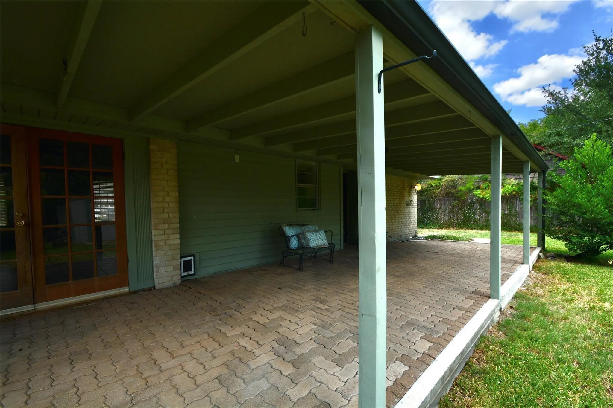 Expansive covered patio featuring a paver stone surface, multiple support columns, and a durable gutter system