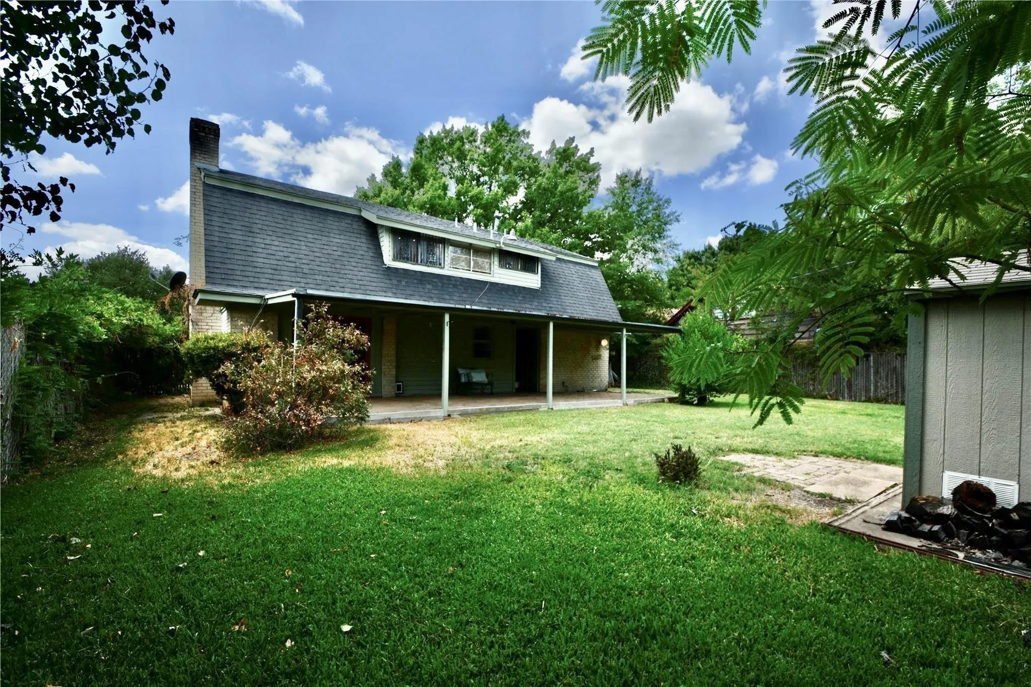 Gambrel roofline property featuring a covered porch, dormer windows, and a prominent chimney