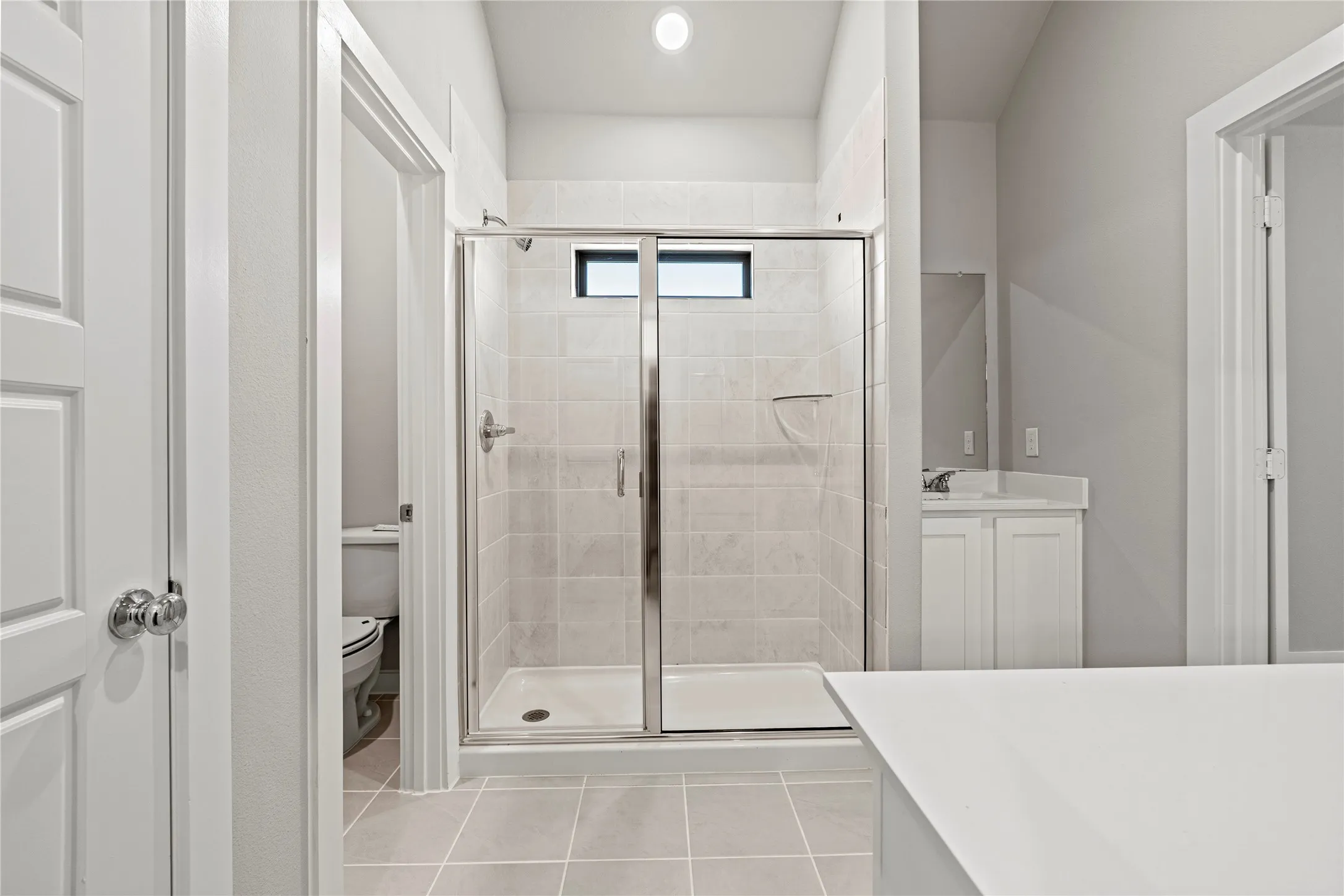 Bathroom with tile flooring, toilet, a shower with door, and vanity
