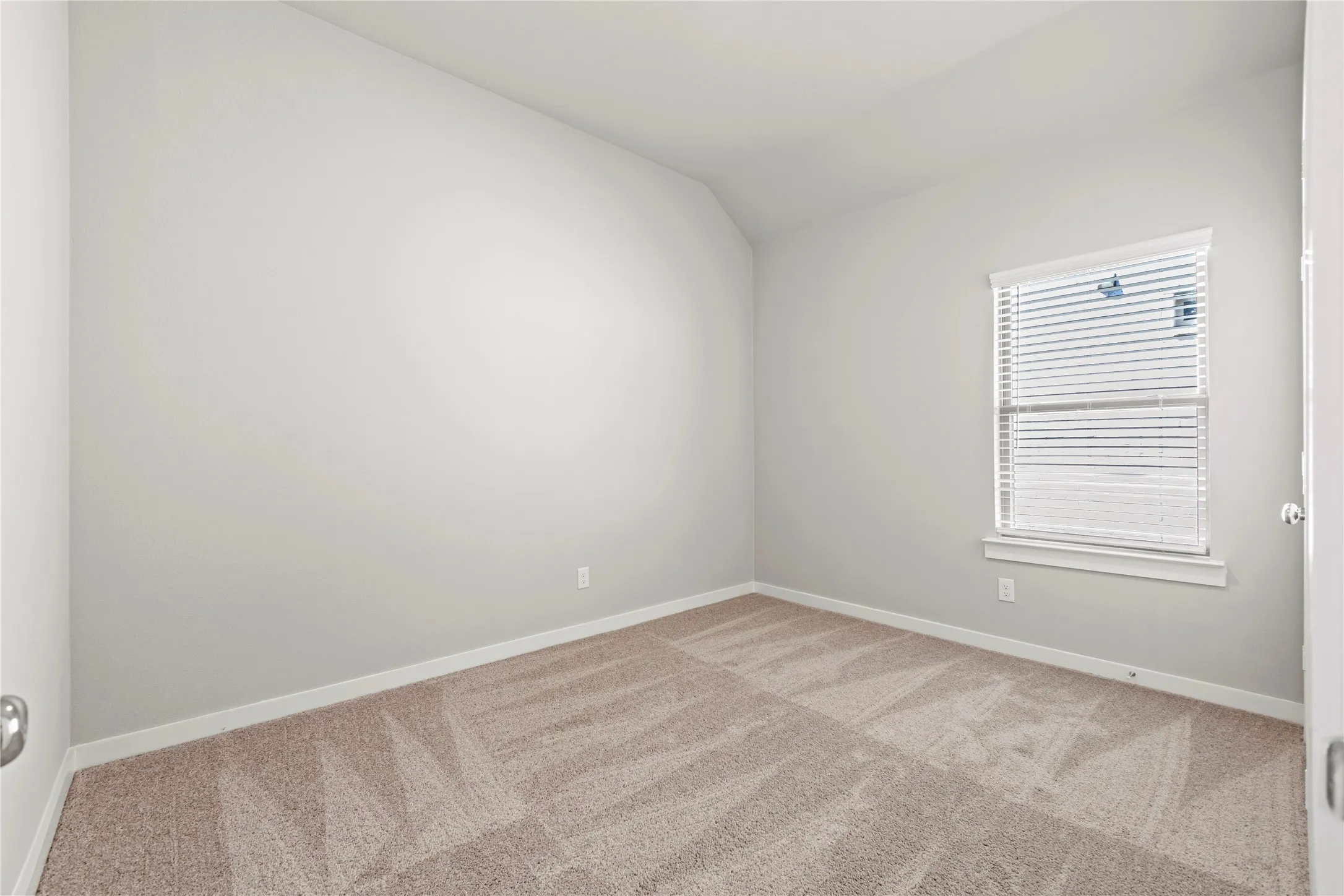 Spare room with light colored carpet and vaulted ceiling