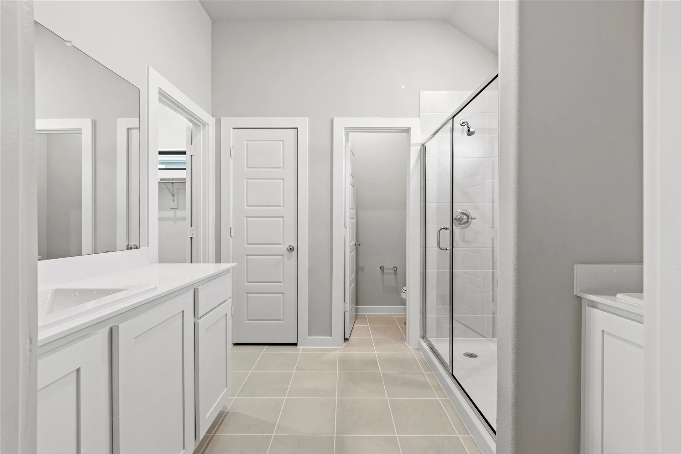 Bathroom with toilet, lofted ceiling, tile flooring, vanity, and an enclosed shower