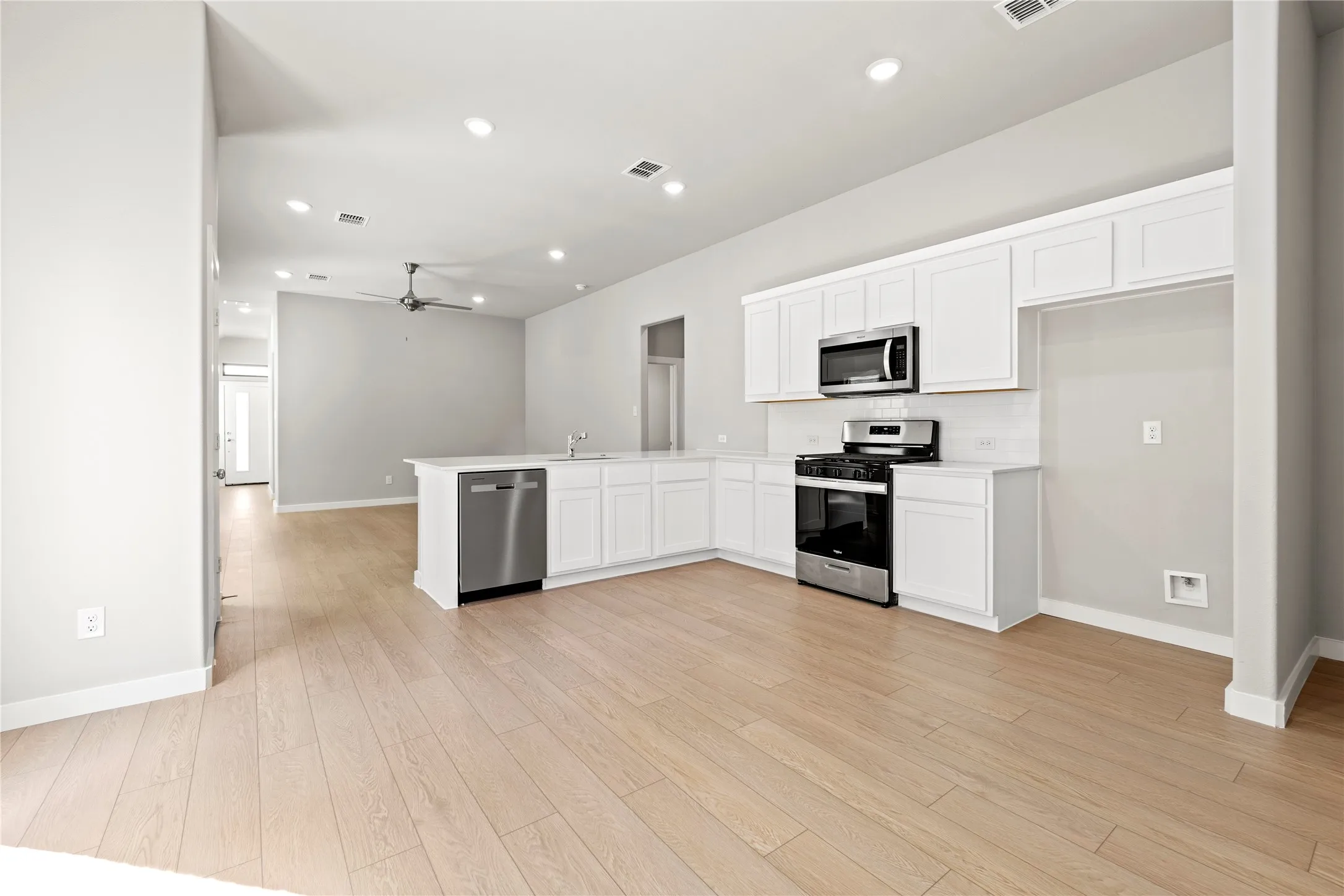Kitchen featuring white cabinets, appliances with stainless steel finishes, and light hardwood / wood-style floors