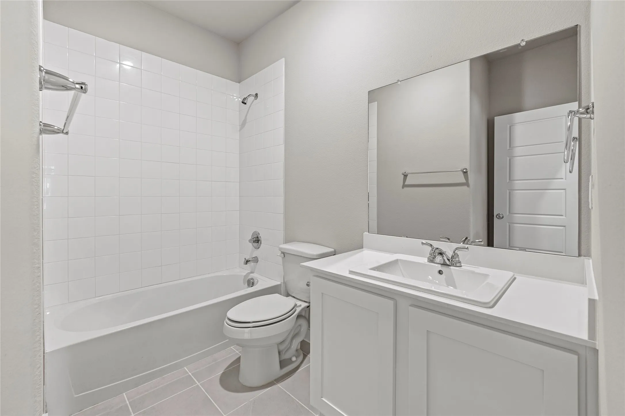 Full bathroom featuring tiled shower / bath combo, toilet, tile flooring, and vanity