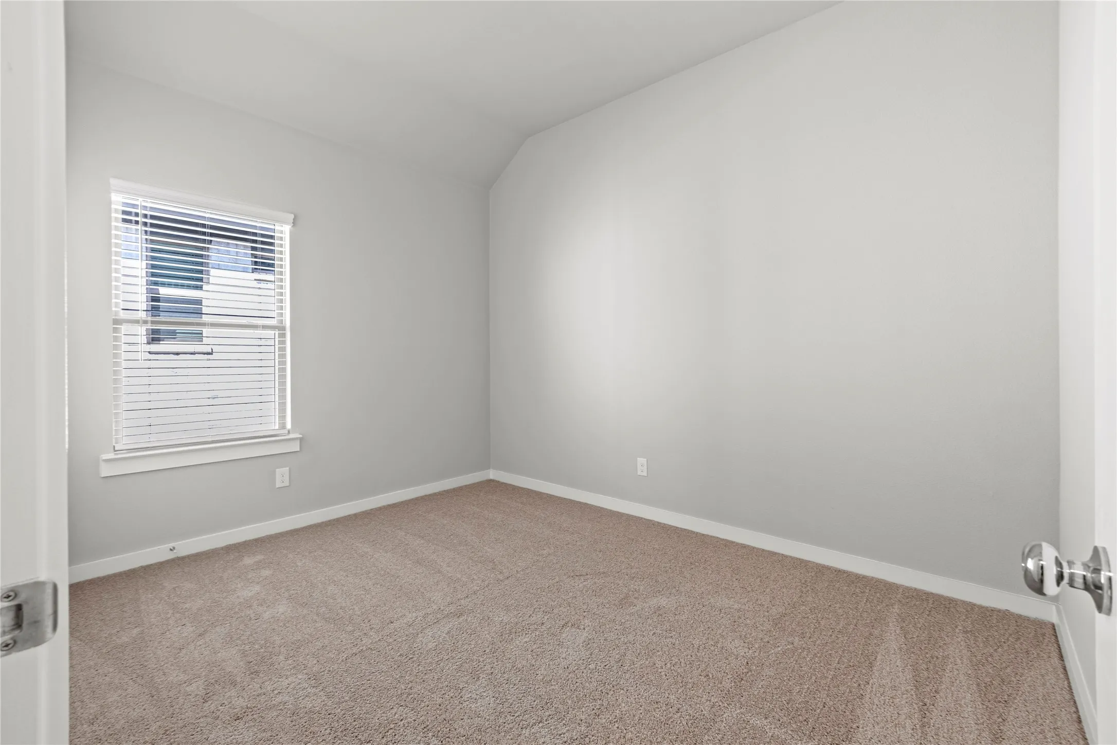 Carpeted spare room with vaulted ceiling