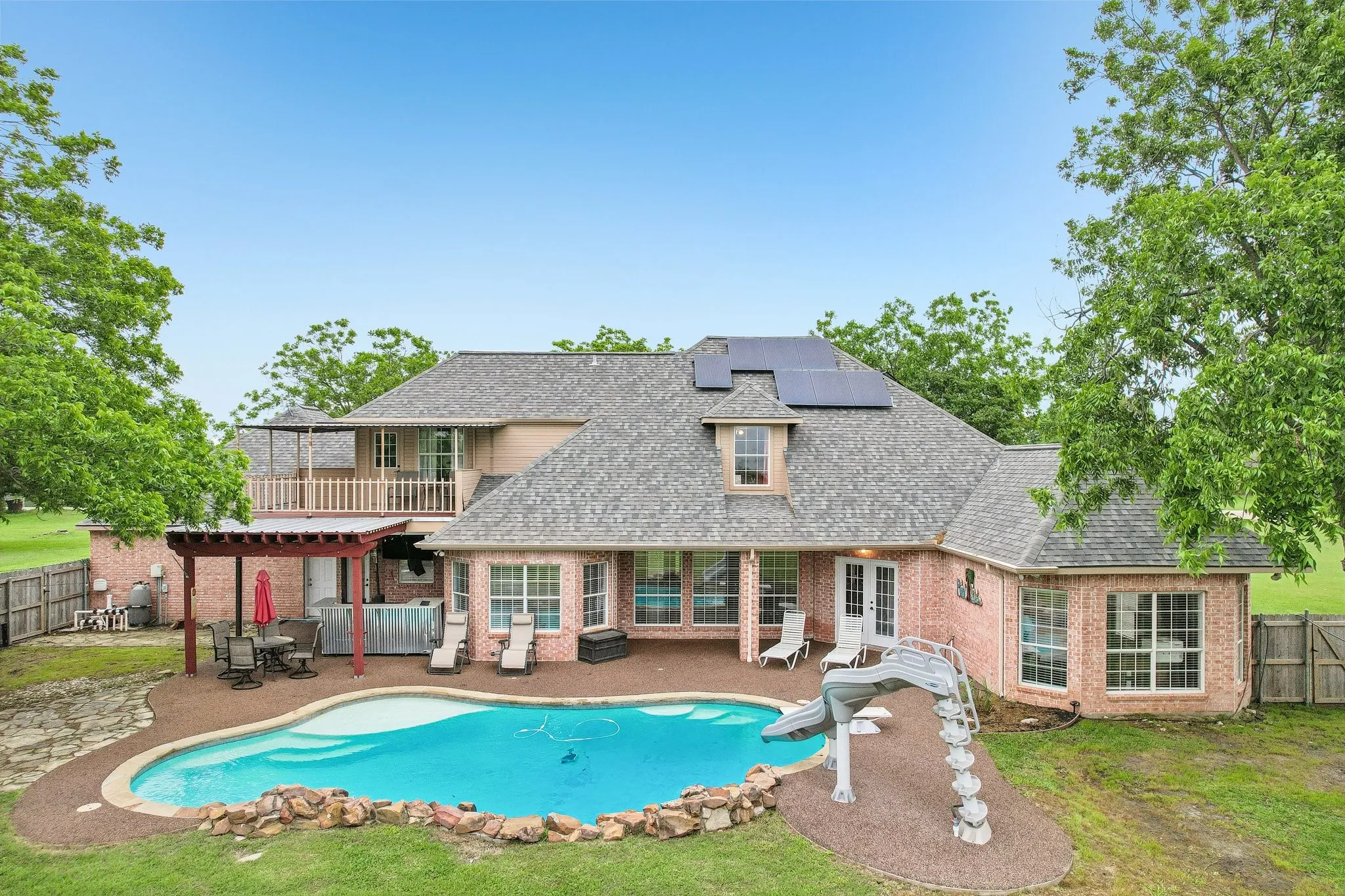Back of the property with patio and pool, finished with a rubber cap surface