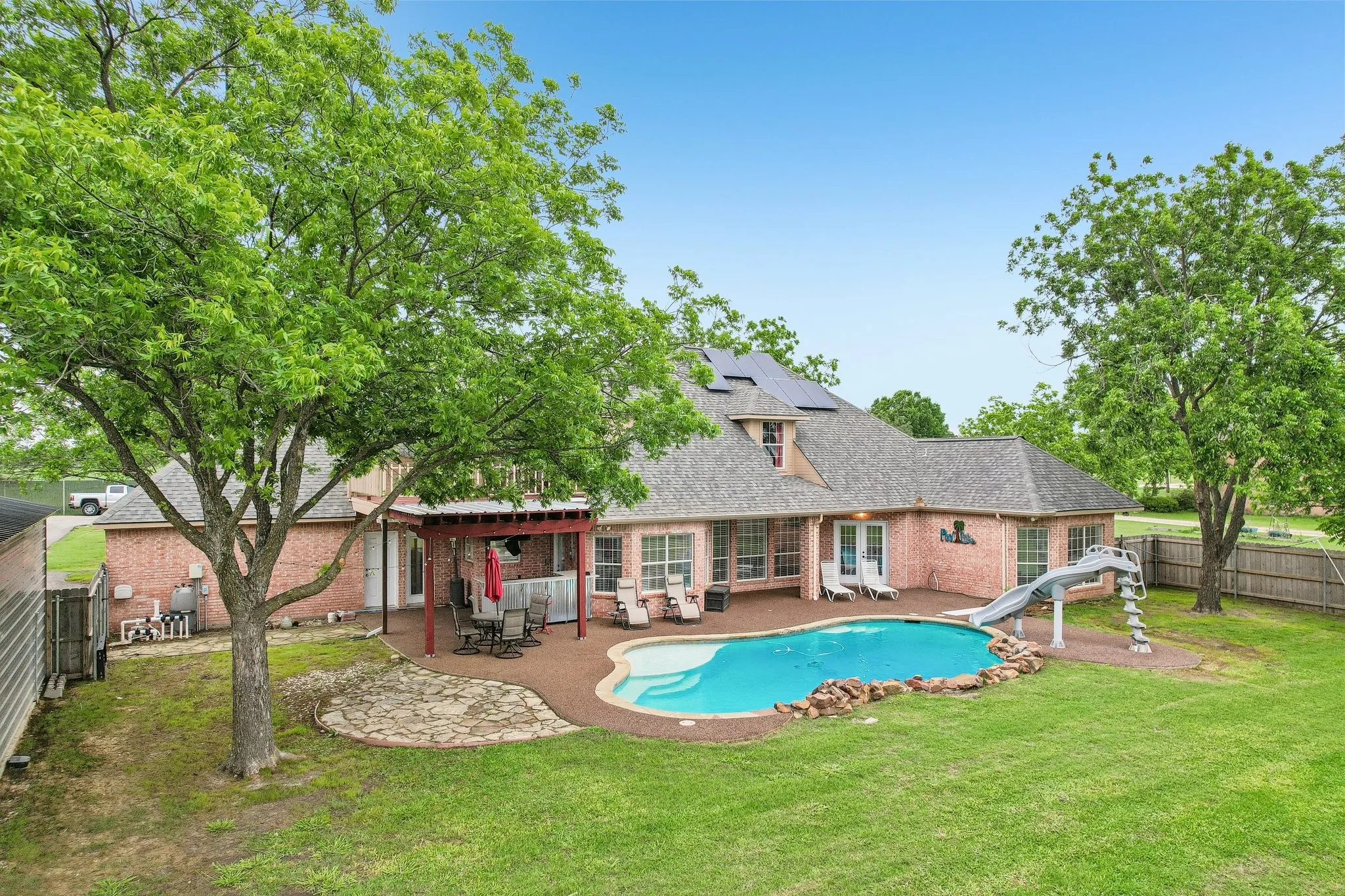 Back of the property with patio and pool, finished with a rubber cap surface