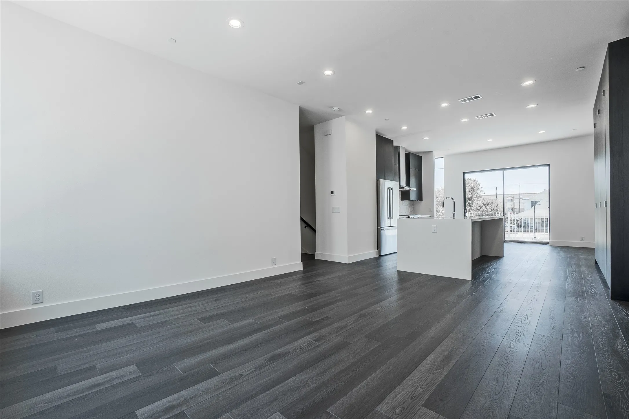 Open-concept living area featuring dark wood-finish flooring, recessed lighting, and a modern kitchen