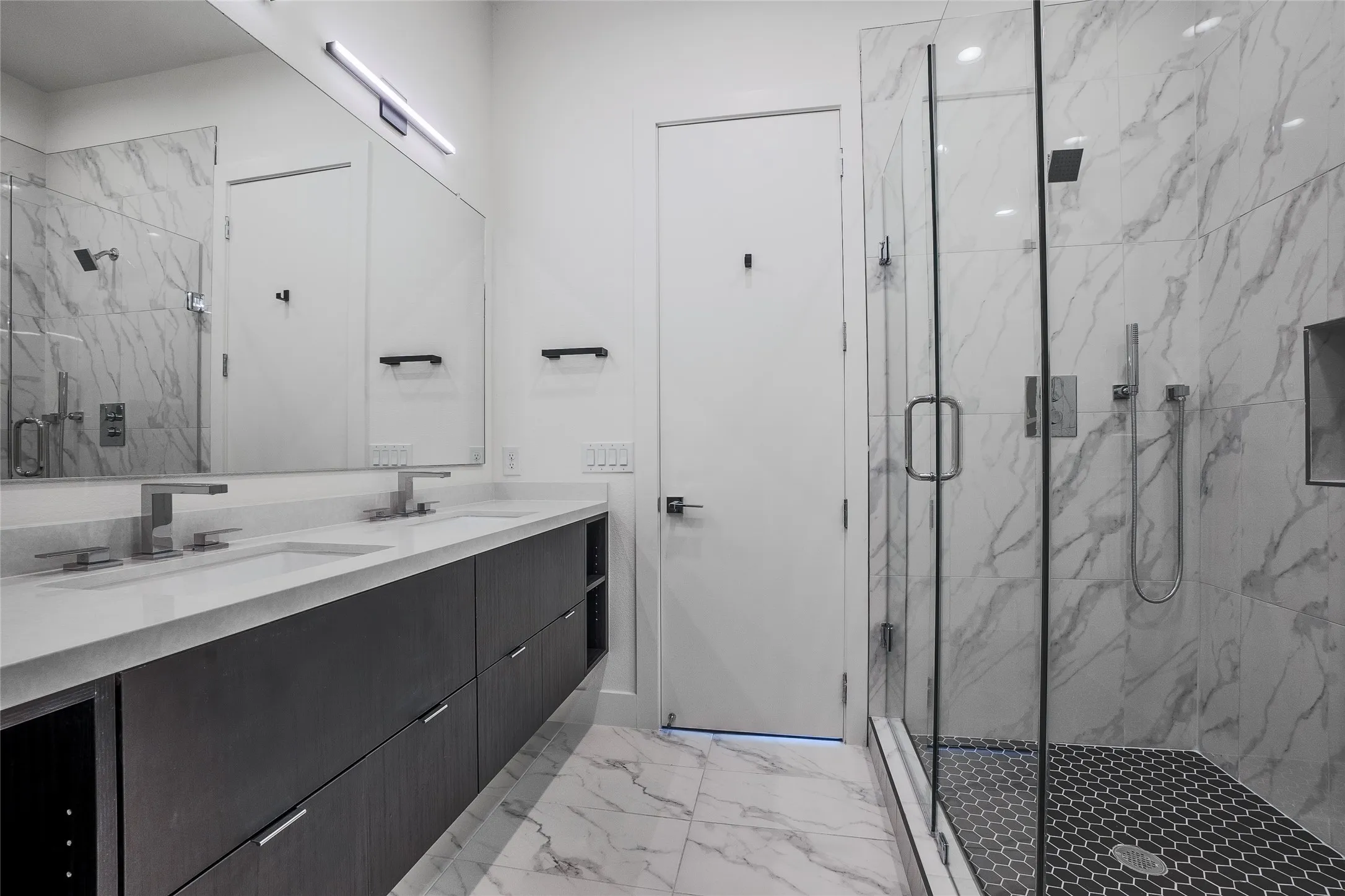 Modern bathroom featuring a dual vanity with a light countertop, dark wood-finish cabinetry, and brushed nickel fixtures