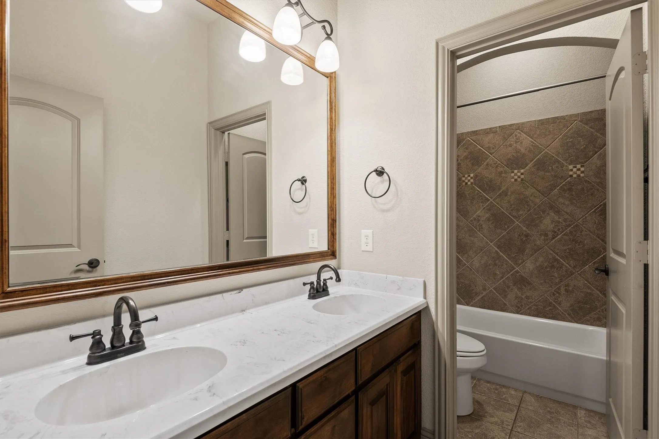 Double vanity with white oval sinks, dark bronze fixtures, and a white marble-finish countertop