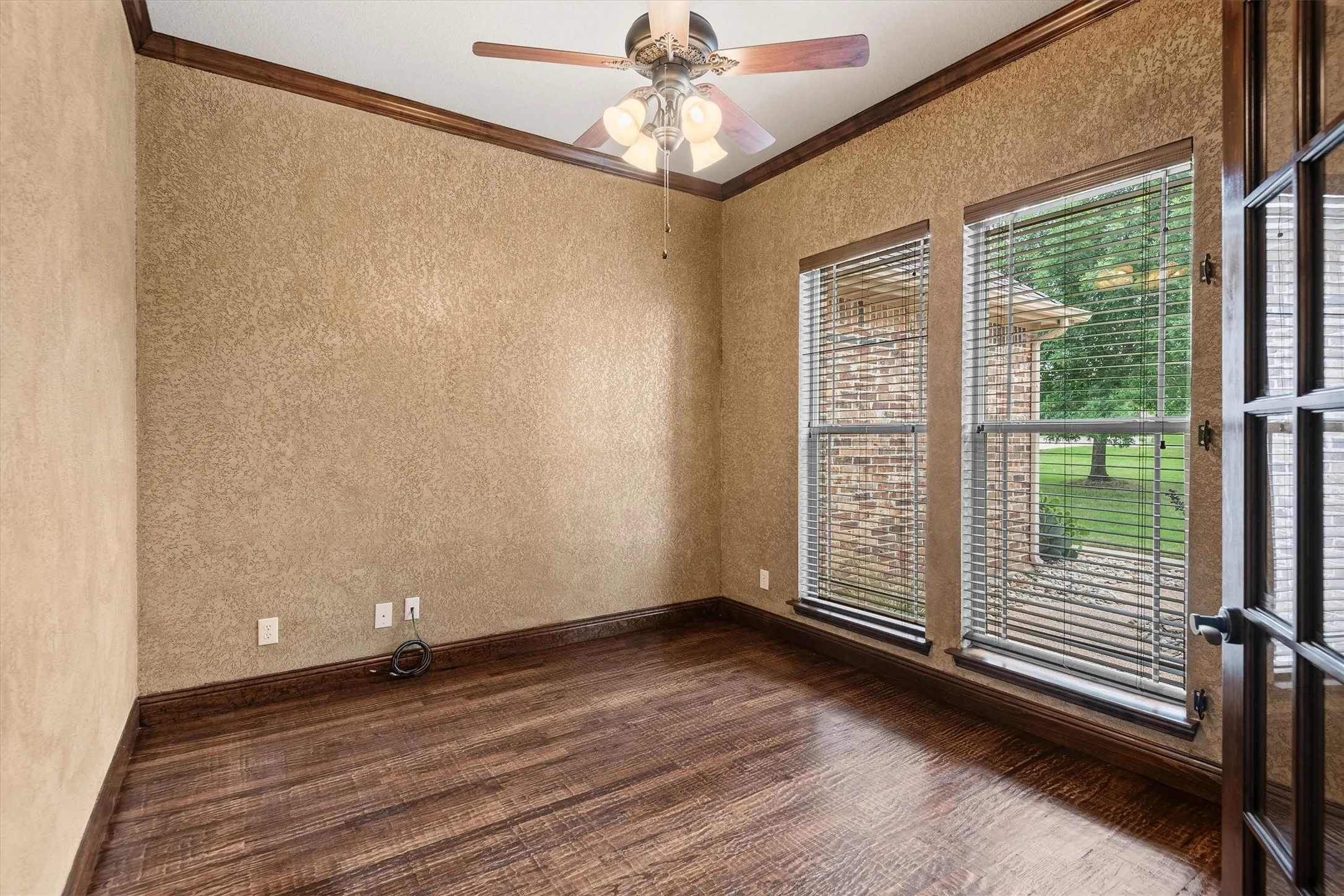Spacious room featuring wood-finish flooring, textured wall finish, and dark wood crown molding