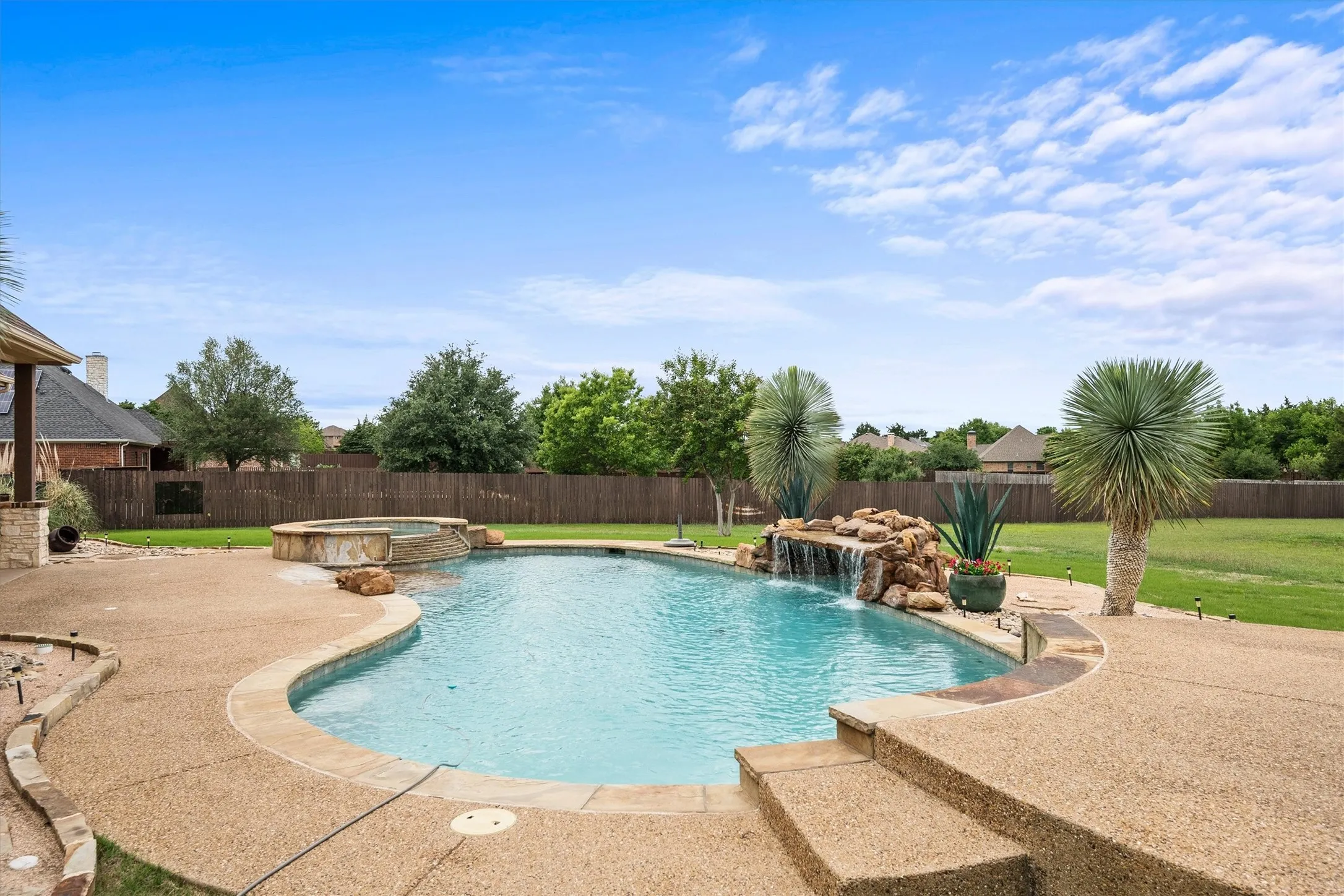 Resort-style backyard featuring a custom-shaped swimming pool with a rock waterfall