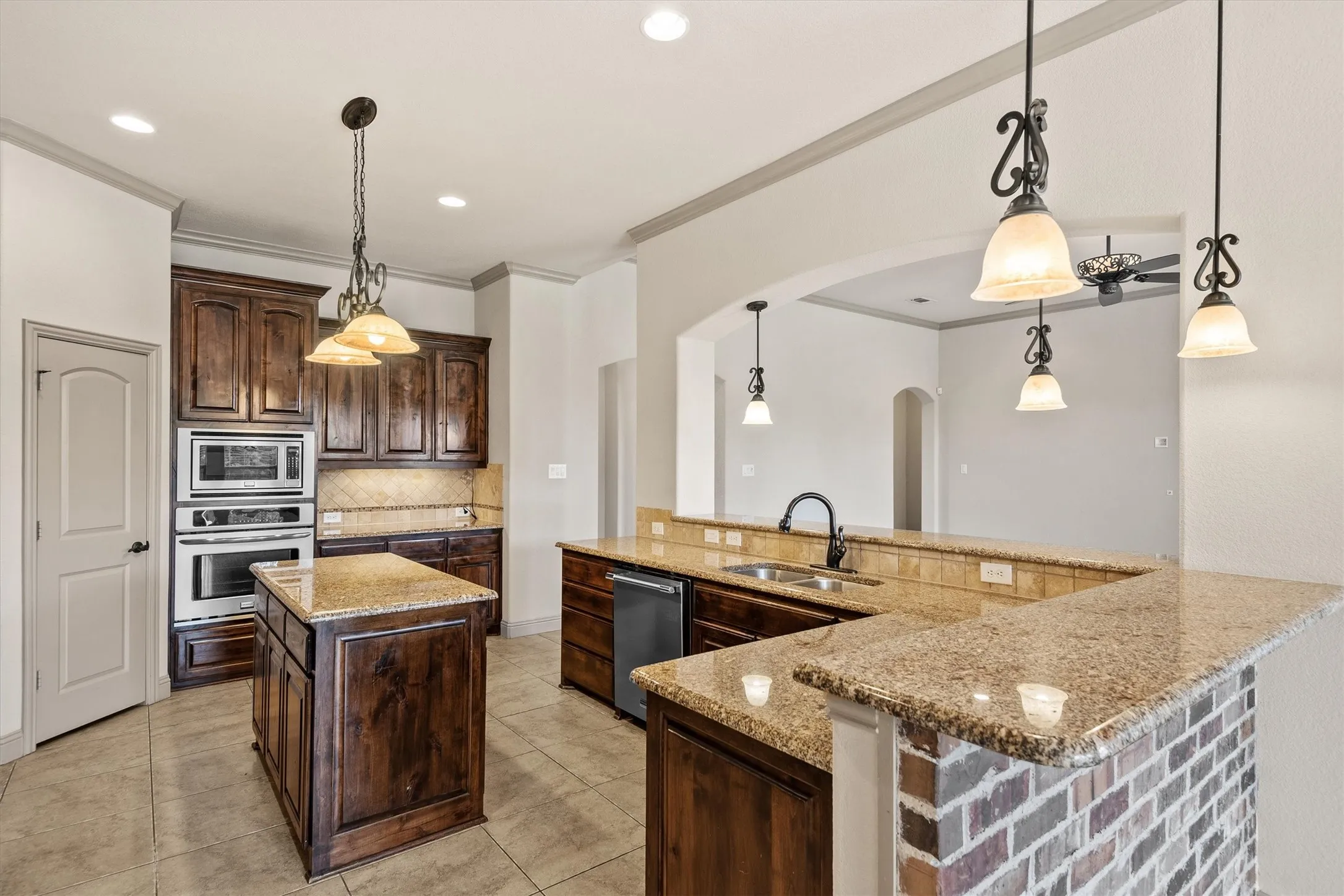 Spacious kitchen featuring dark wood cabinetry, a central island, and light-colored tiled flooring