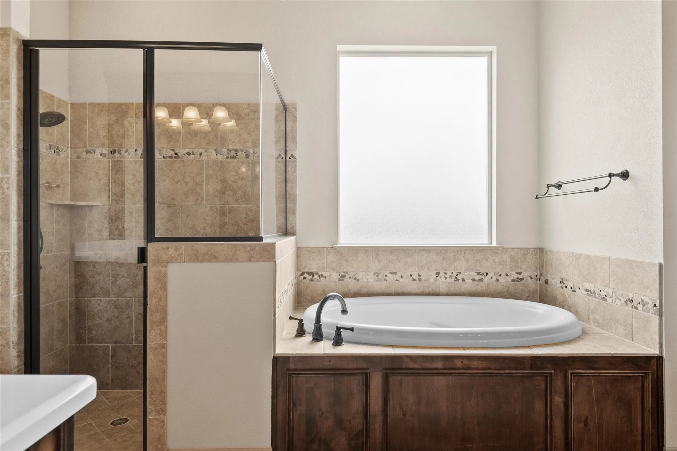 Soaking tub with dark wood-finish paneling, complemented by a tiled surround and opaque window