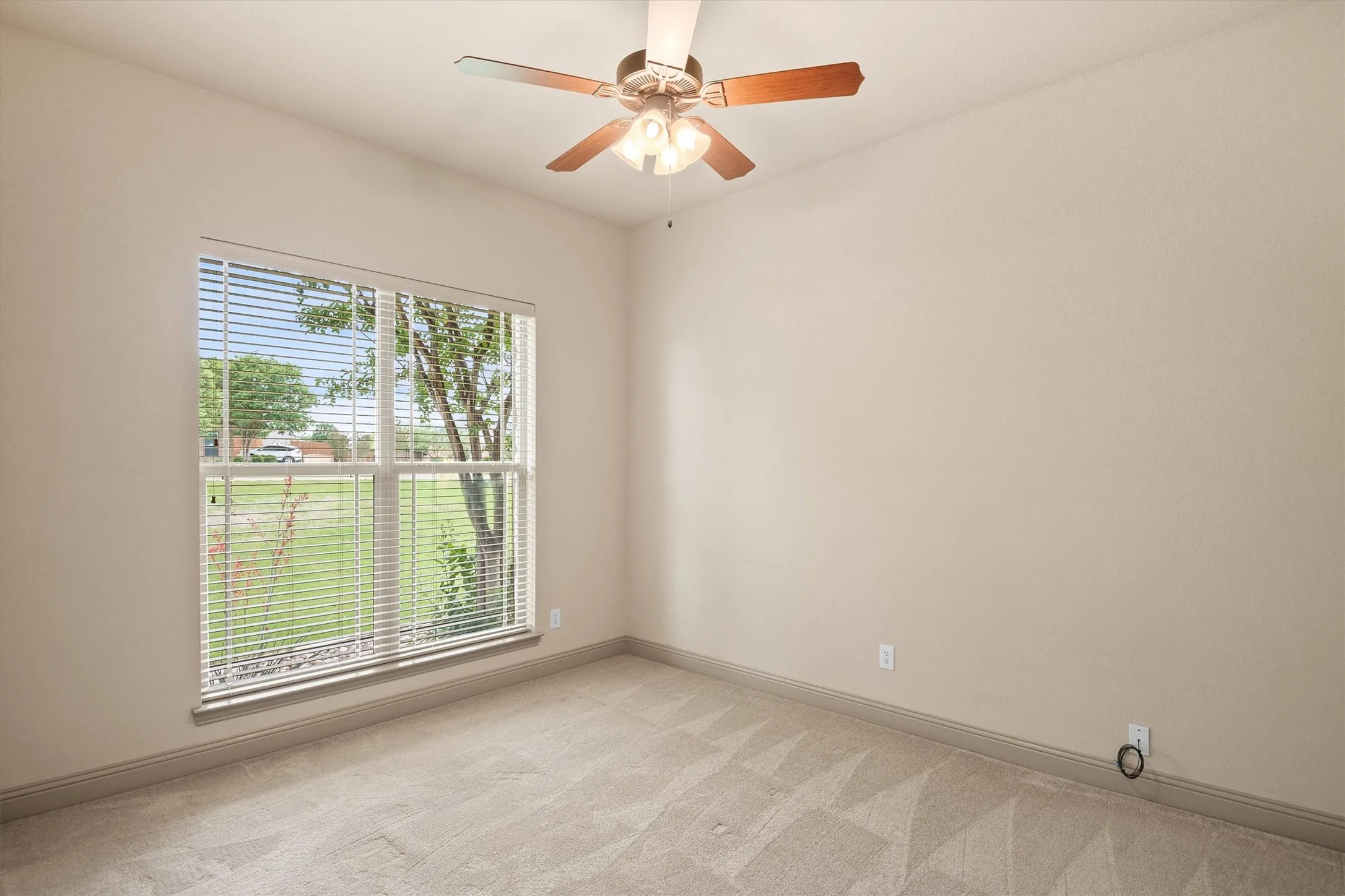 Carpeted room featuring a ceiling fan with integrated lighting, a large window with blinds, and neutral wall paint
