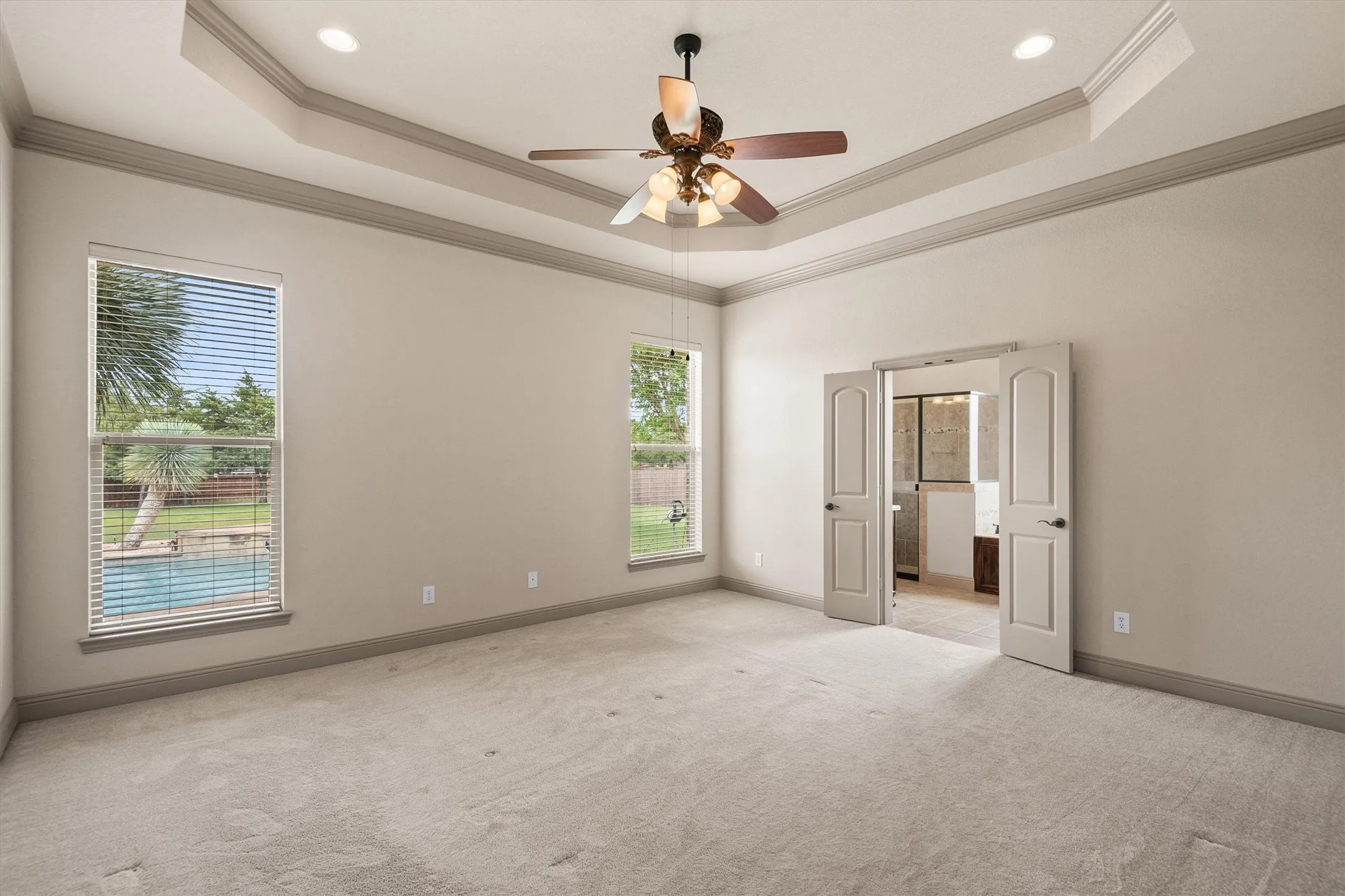 Spacious room featuring a tray ceiling with recessed lighting and a ceiling fan