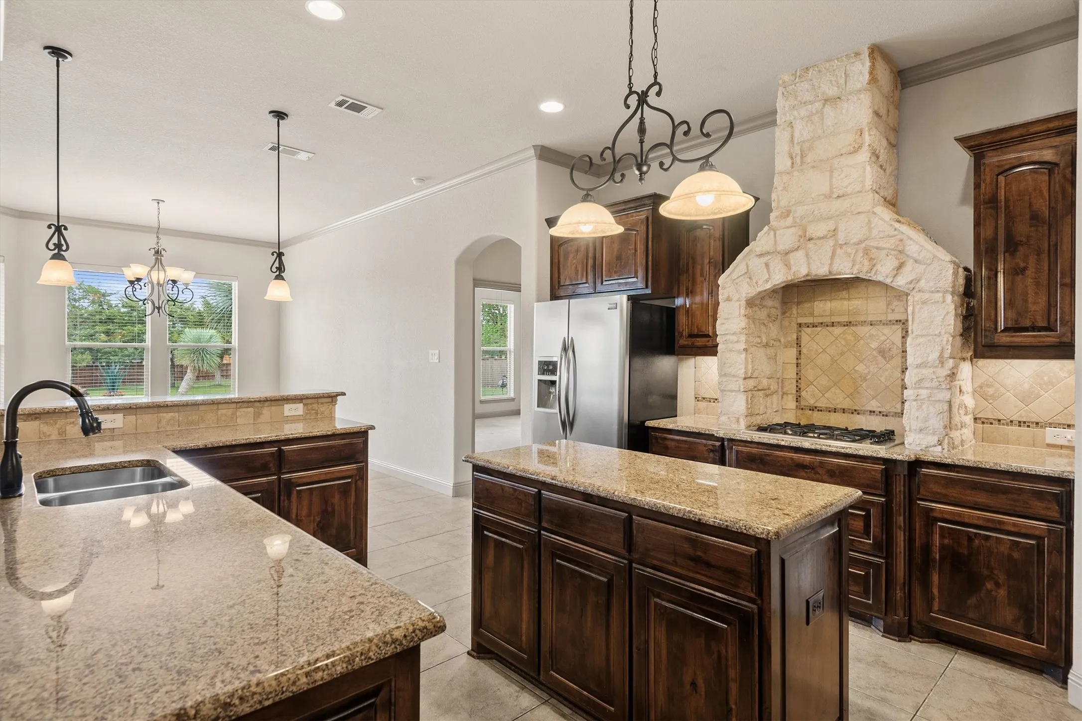 Kitchen featuring dark wood cabinetry, light-toned countertops, a stone-clad range hood, and stainless steel appliances