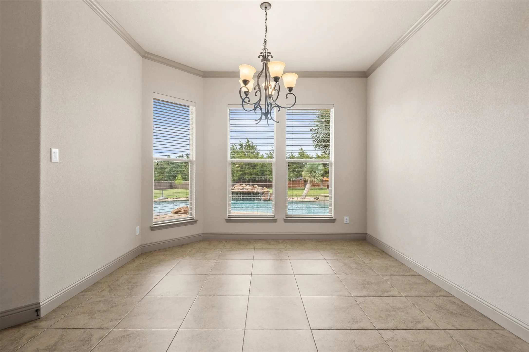 Interior room featuring tile flooring, crown molding, and baseboards