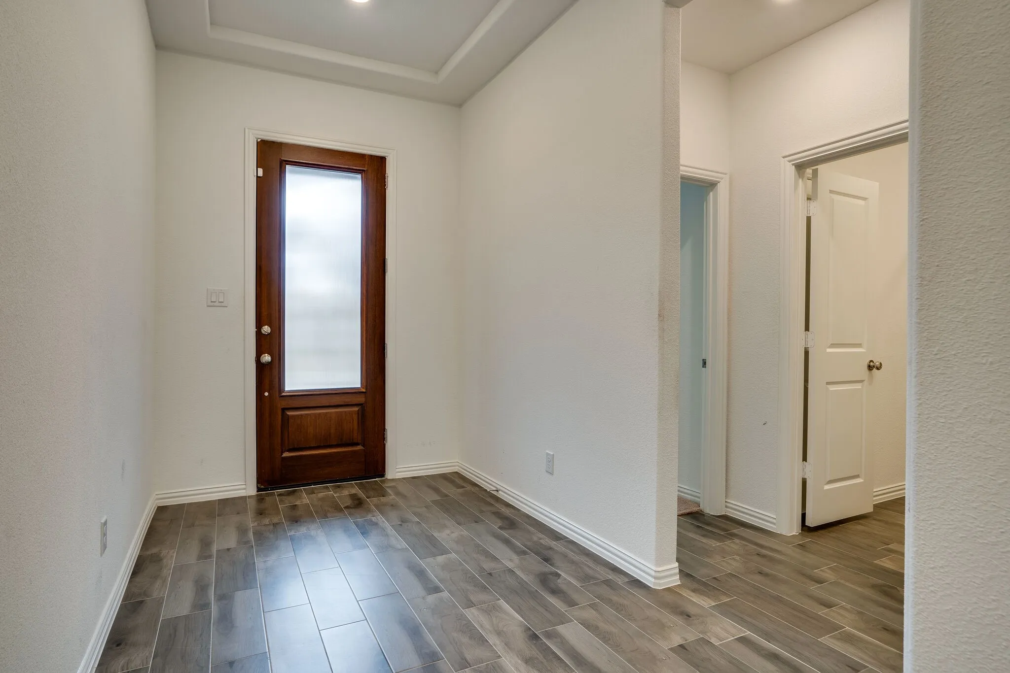 Entryway featuring a wood-finish door with frosted glass panel, recessed lighting, crown molding, and wood-look tile flooring