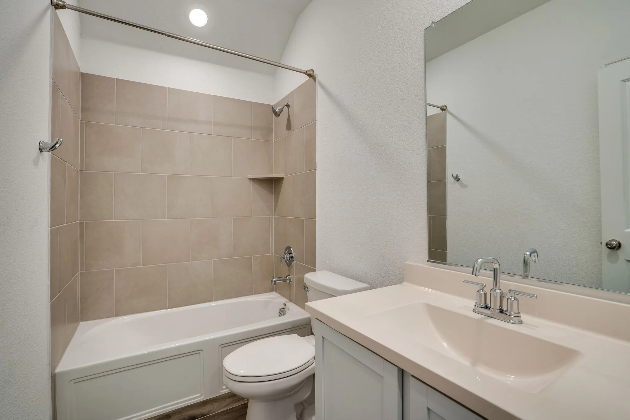 Full bathroom featuring a single vanity with an integrated sink, a large wall-mounted mirror, and a bathtub with beige subway tile surround