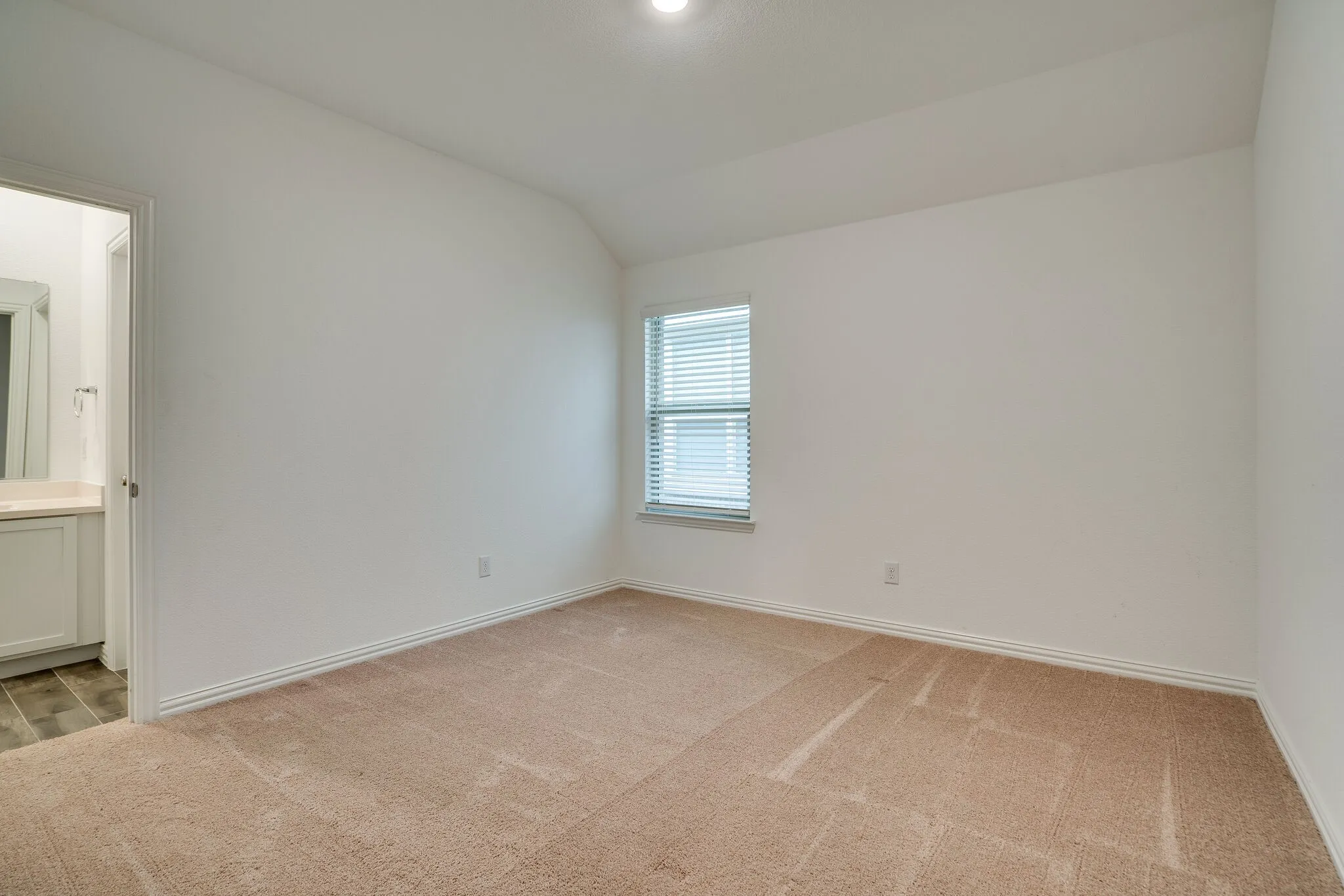 Carpeted room with a single window featuring blinds