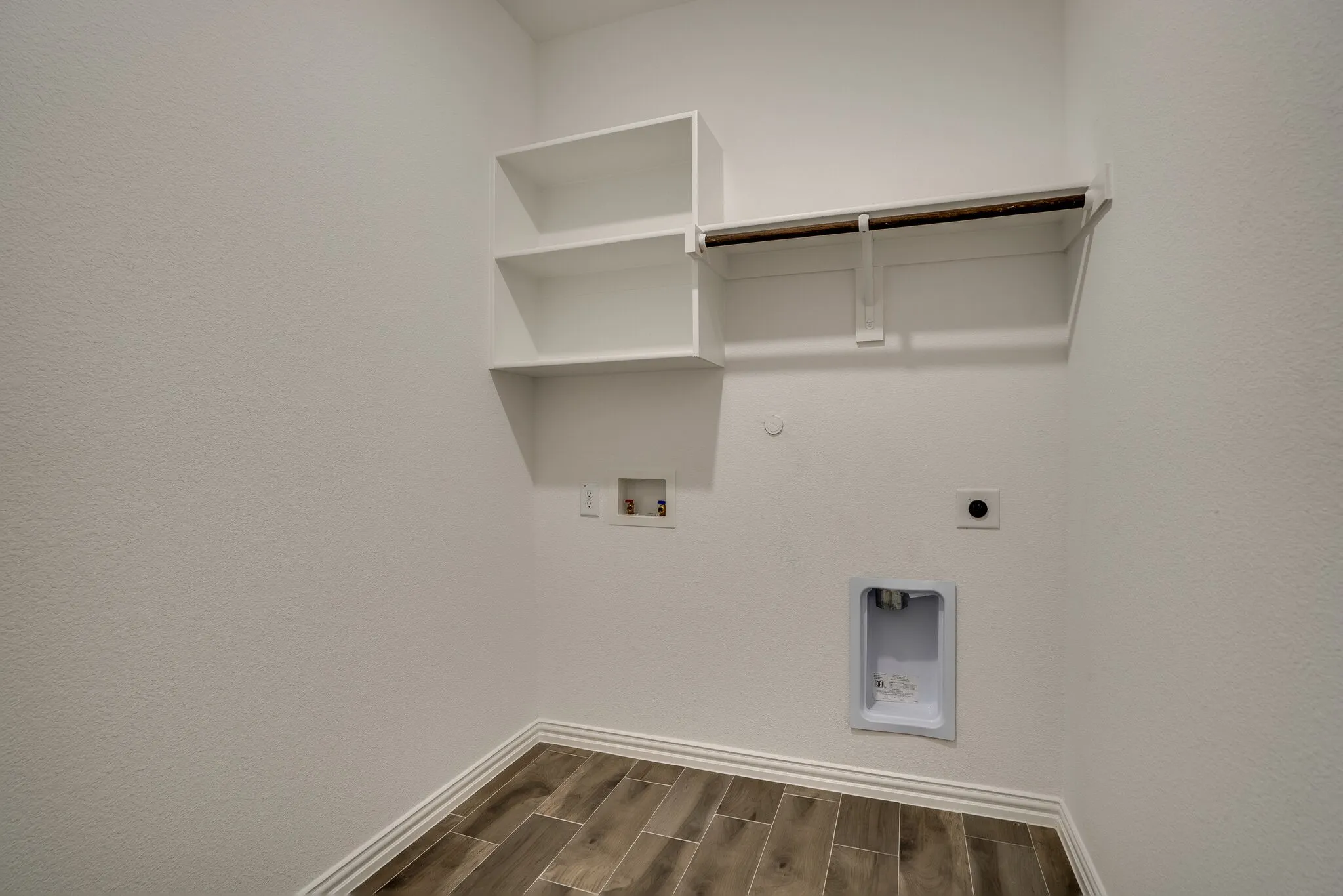 Utility area featuring wood-finish flooring, white baseboards, and built-in white shelving