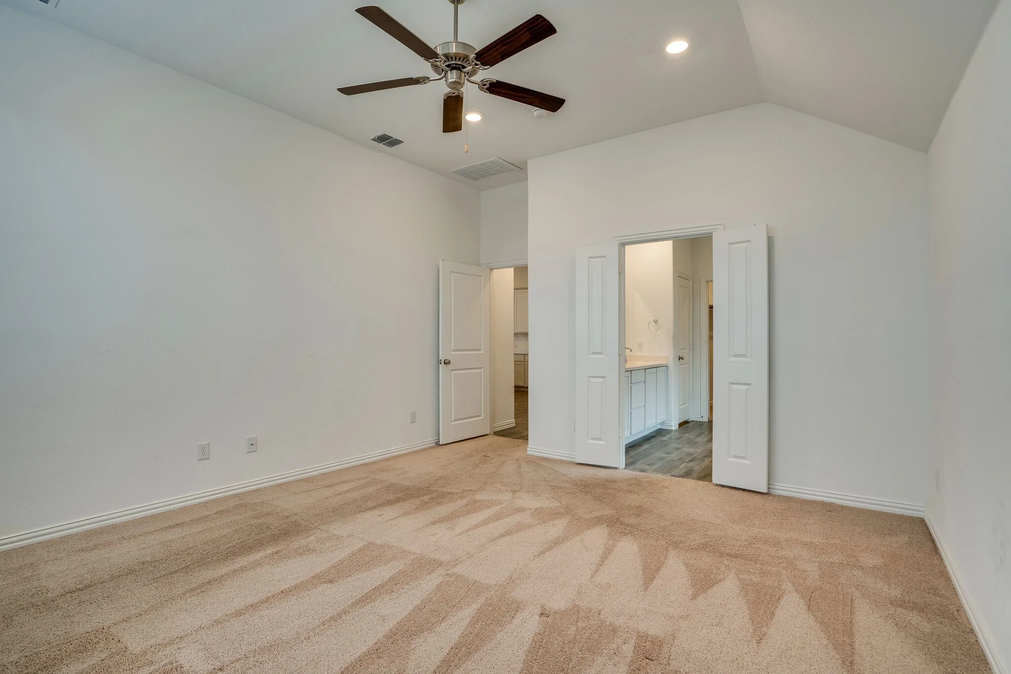 Carpeted room featuring a vaulted ceiling with a ceiling fan and recessed lighting
