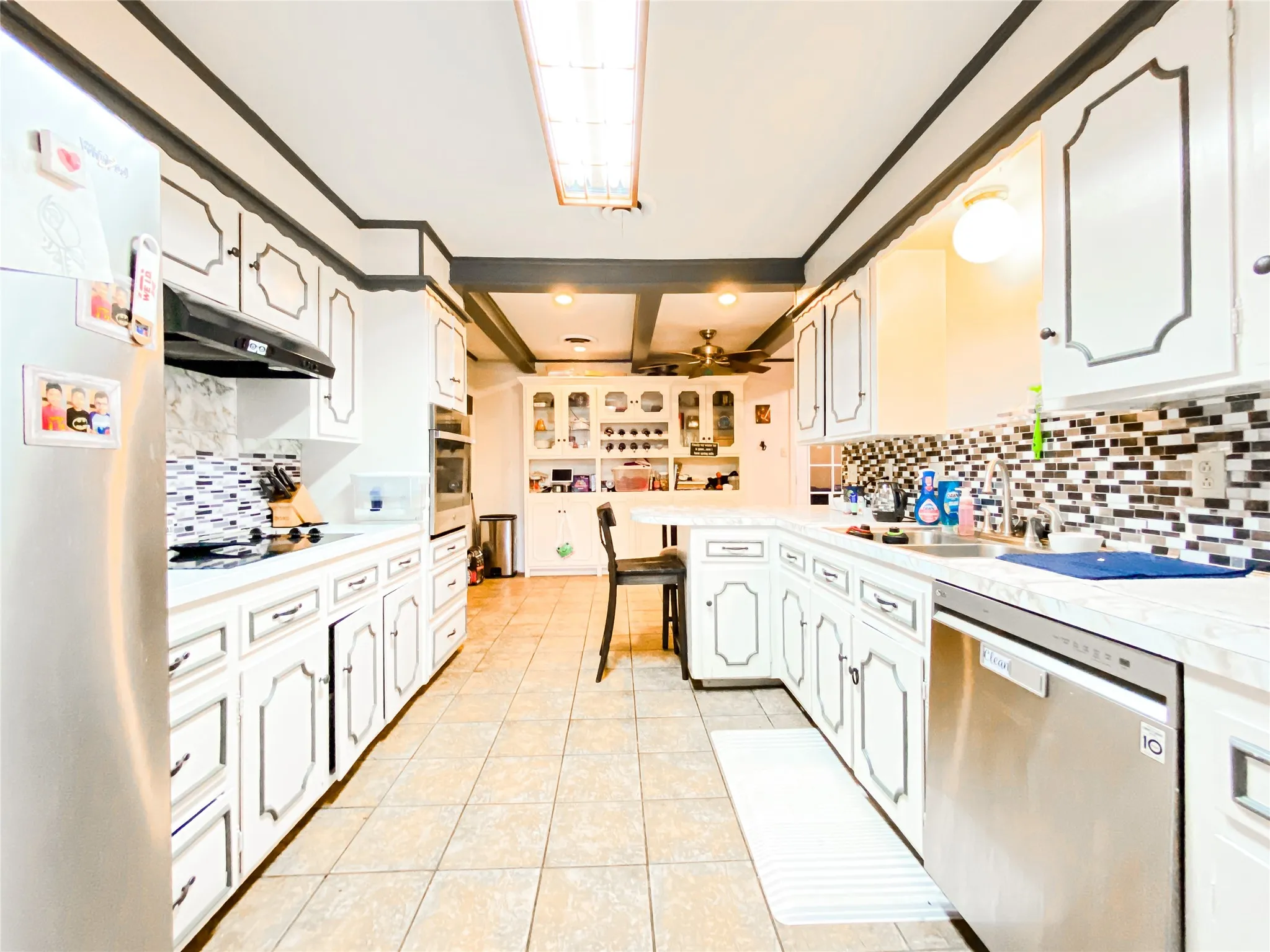 Galley kitchen with extensive white cabinetry featuring dark trim, a mosaic tile backsplash, and light-toned countertops
