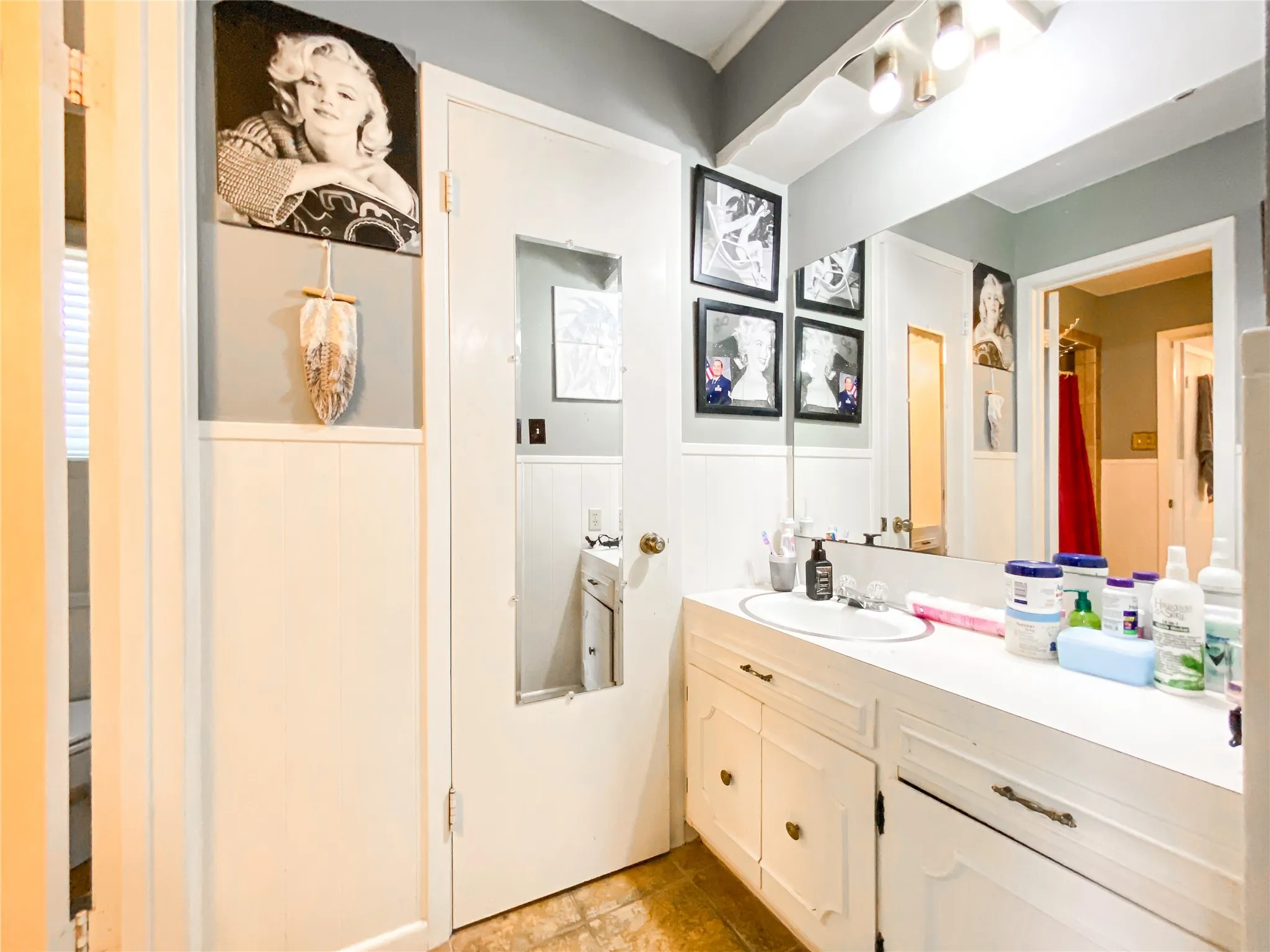 Bathroom vanity featuring a built-in sink, white cabinetry, and a large wall-mounted mirror