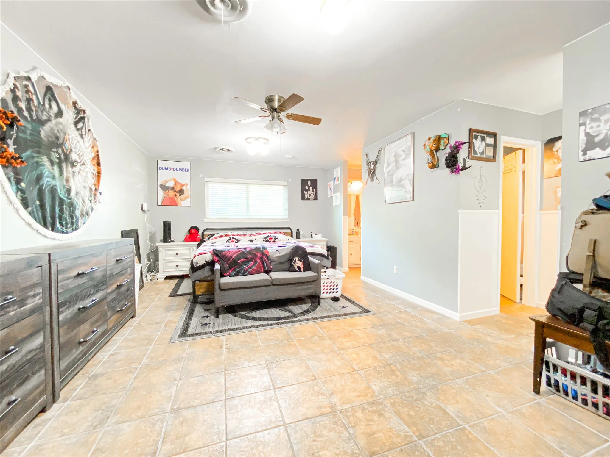 Spacious interior room featuring neutral wall tones, tile flooring, and a ceiling fan