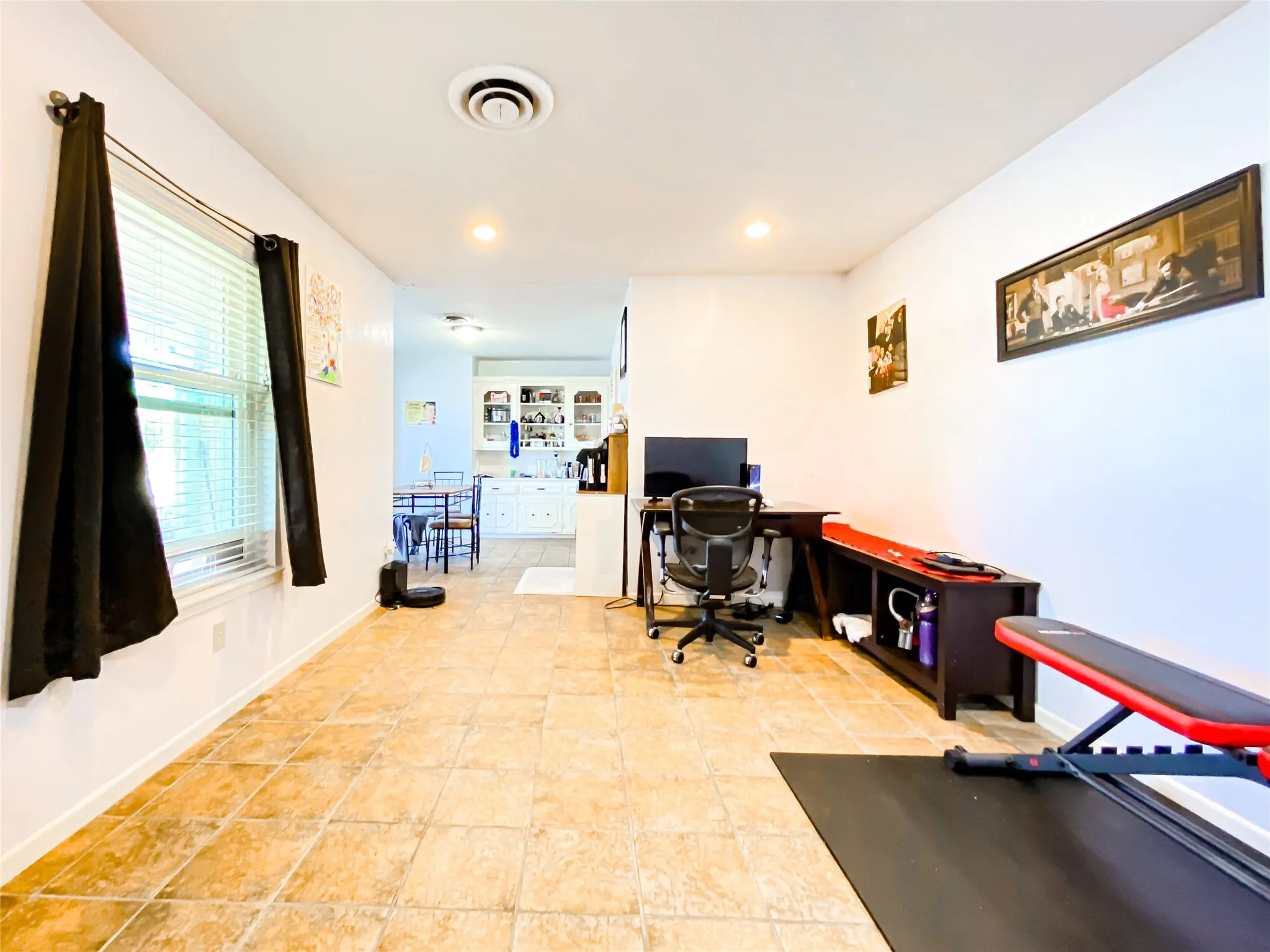 Spacious interior featuring tile flooring, white walls, recessed lighting, and a window with blinds