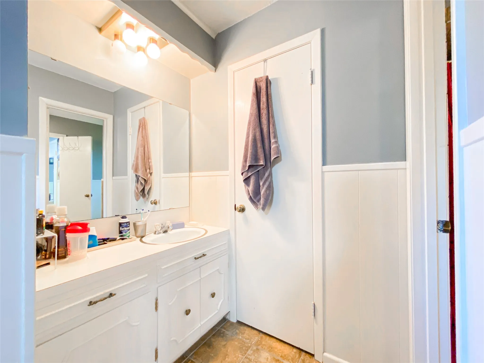 Bathroom vanity featuring a white countertop with integrated sink, white cabinetry, and a full-width mirror