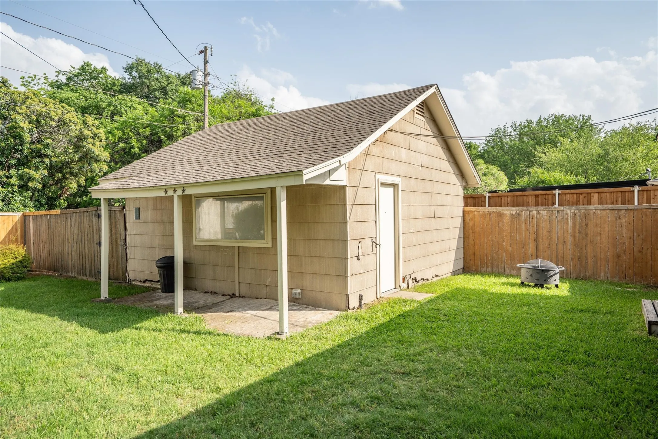 Detached utility building with shingle roofing, horizontal siding, and a covered concrete patio