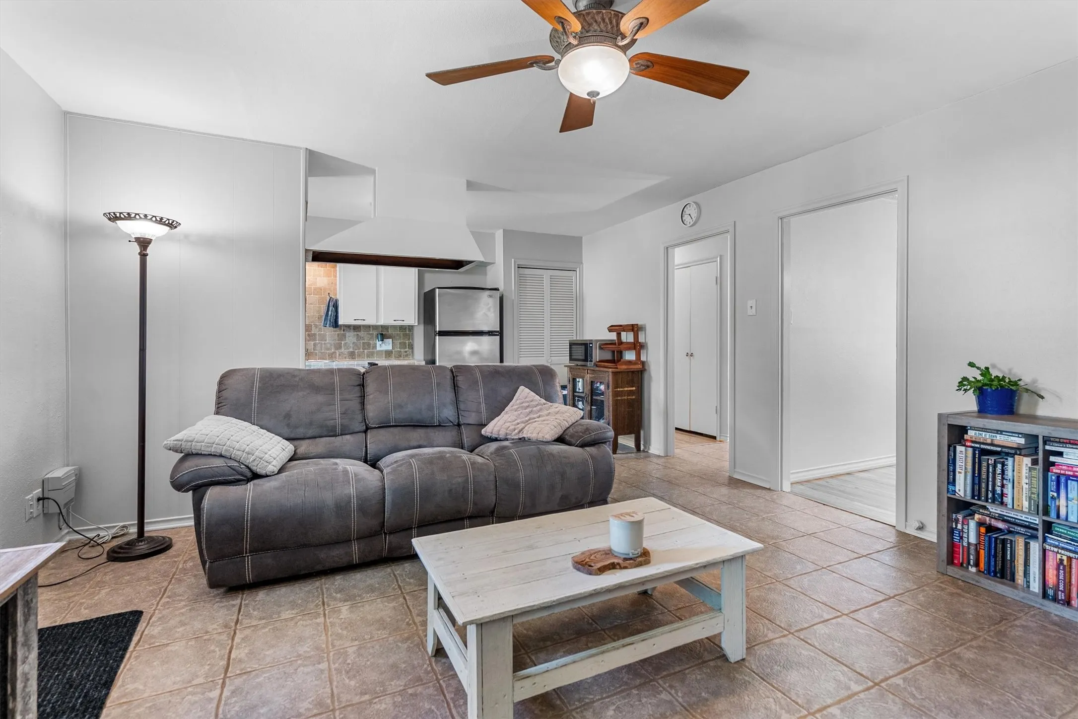 Living area featuring neutral wall tones, tile flooring, and a ceiling fan with integrated lighting