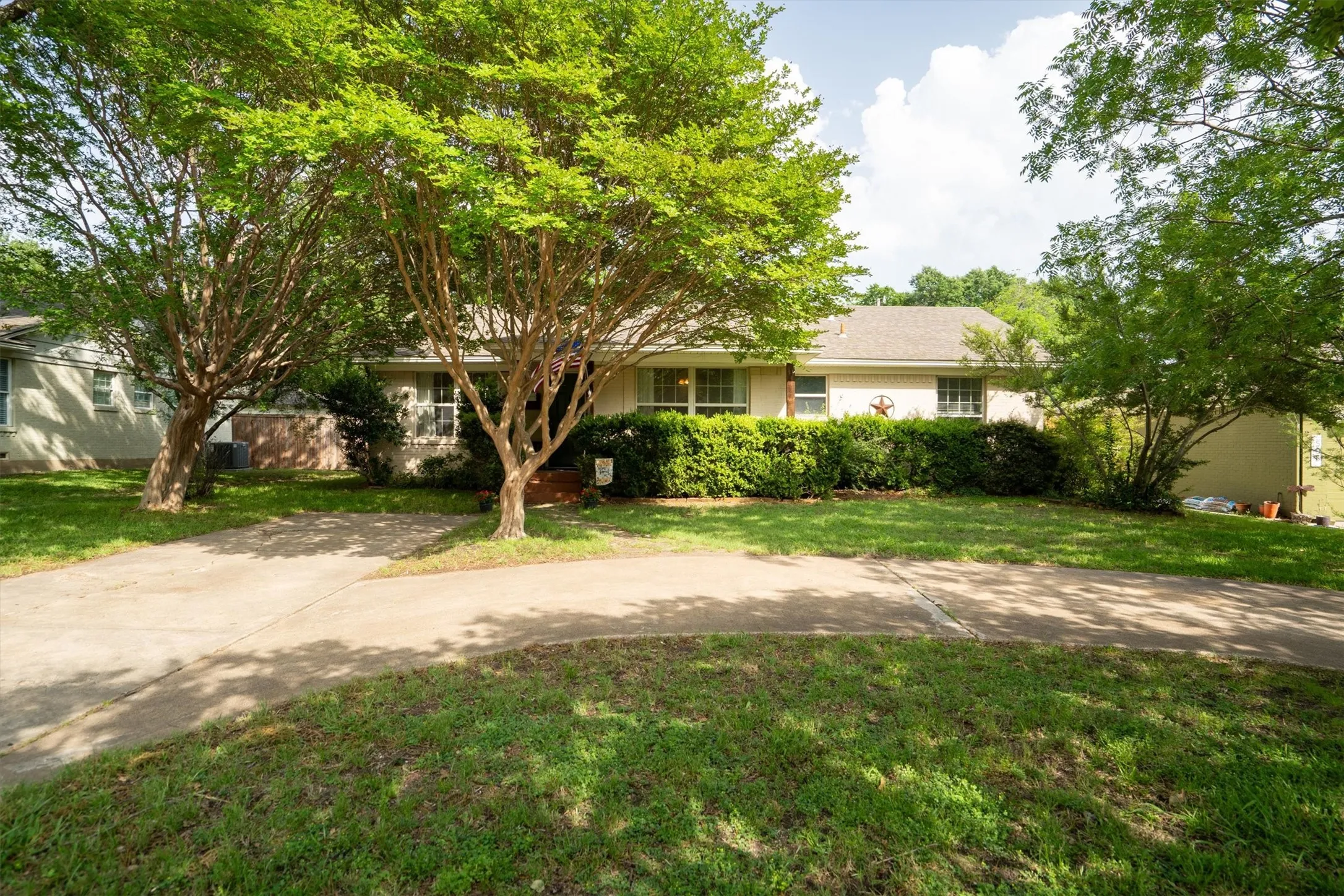 Ranch-style residence featuring a light-colored exterior and a traditional shingled roof
