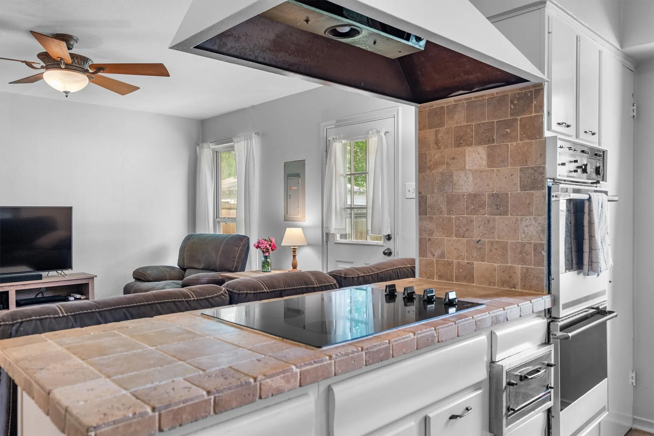 Kitchen counter with tile surfacing, integrated cooktop, and an adjacent built-in double oven